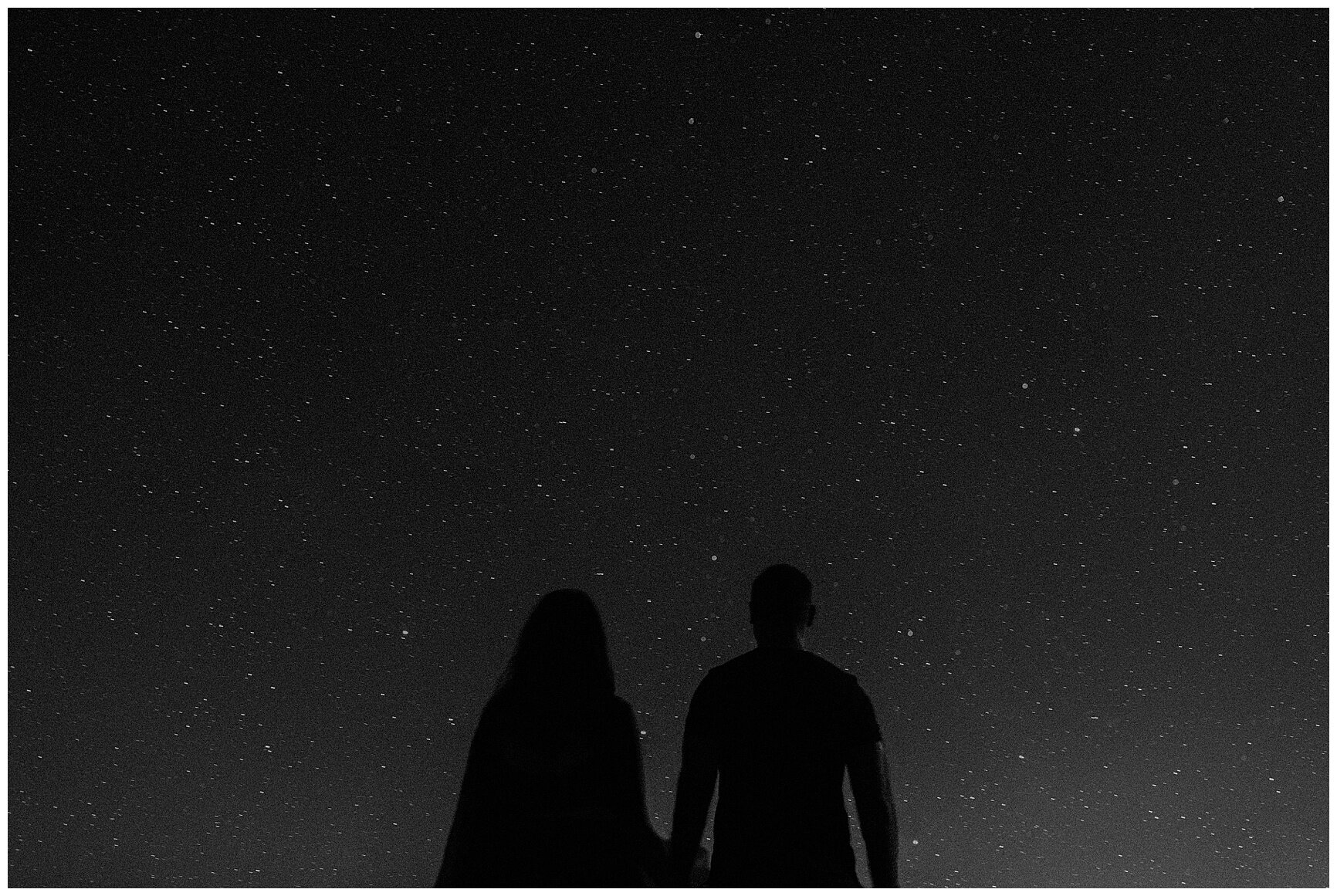 engaged couple holding hands under the starry night sky in the desert in monument valley arizona
