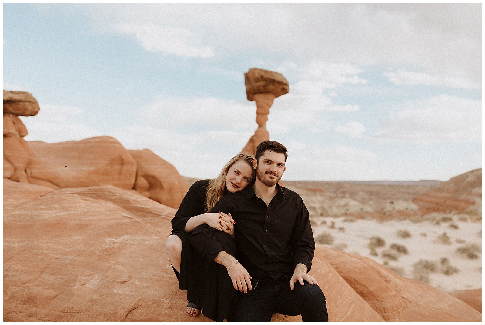 engaged couple wearing black and posing for portraits in grand escalante