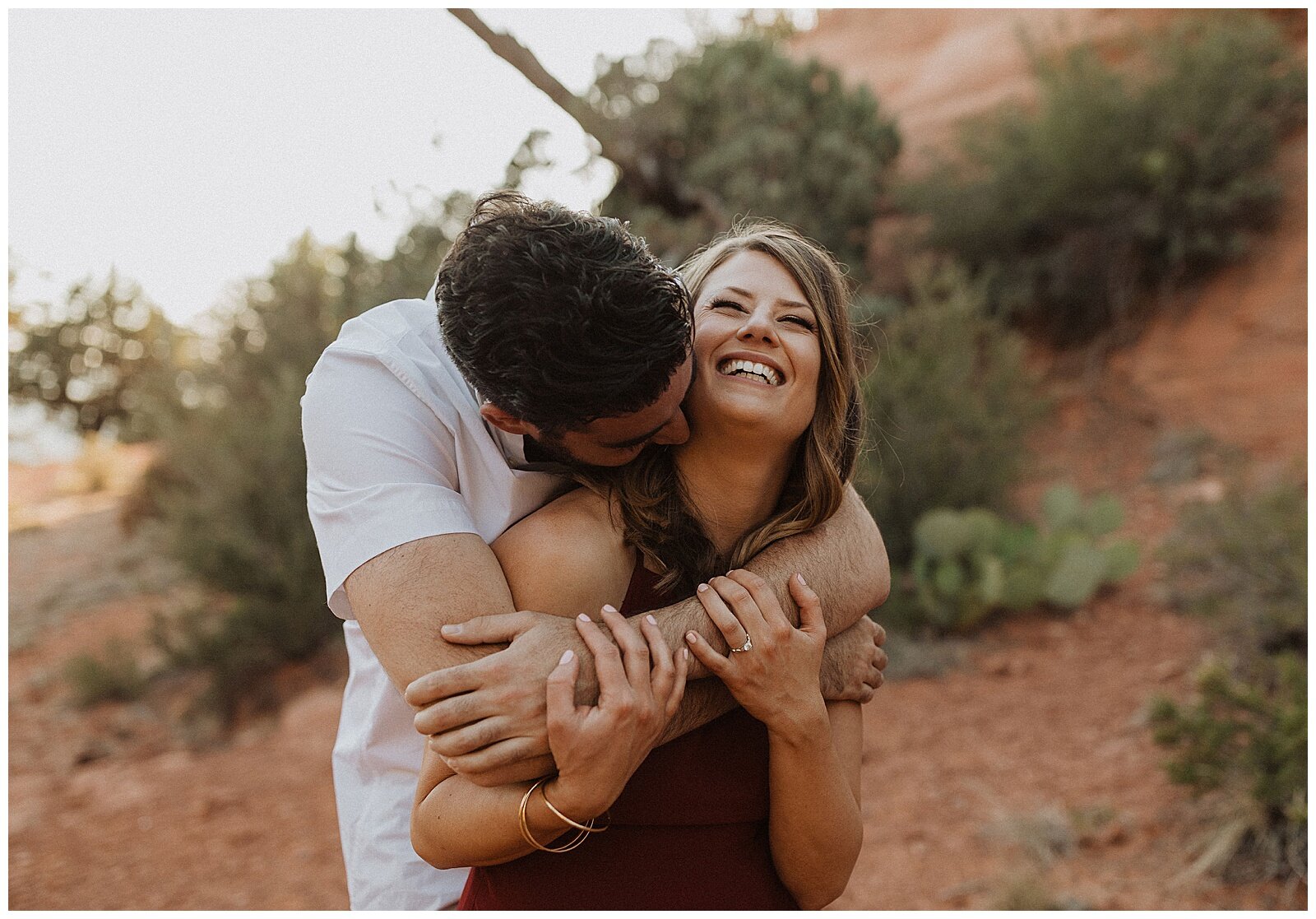 couple hugging in front of red rocks for their sedona engagement session 