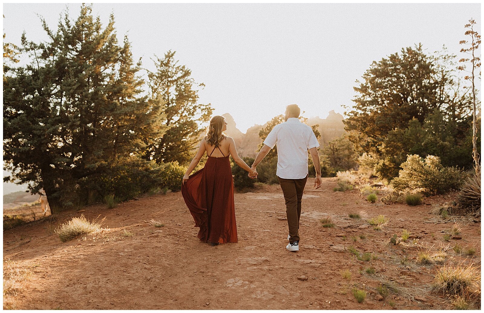 couple holding hands in front of red rocks for their sedona engagement session 