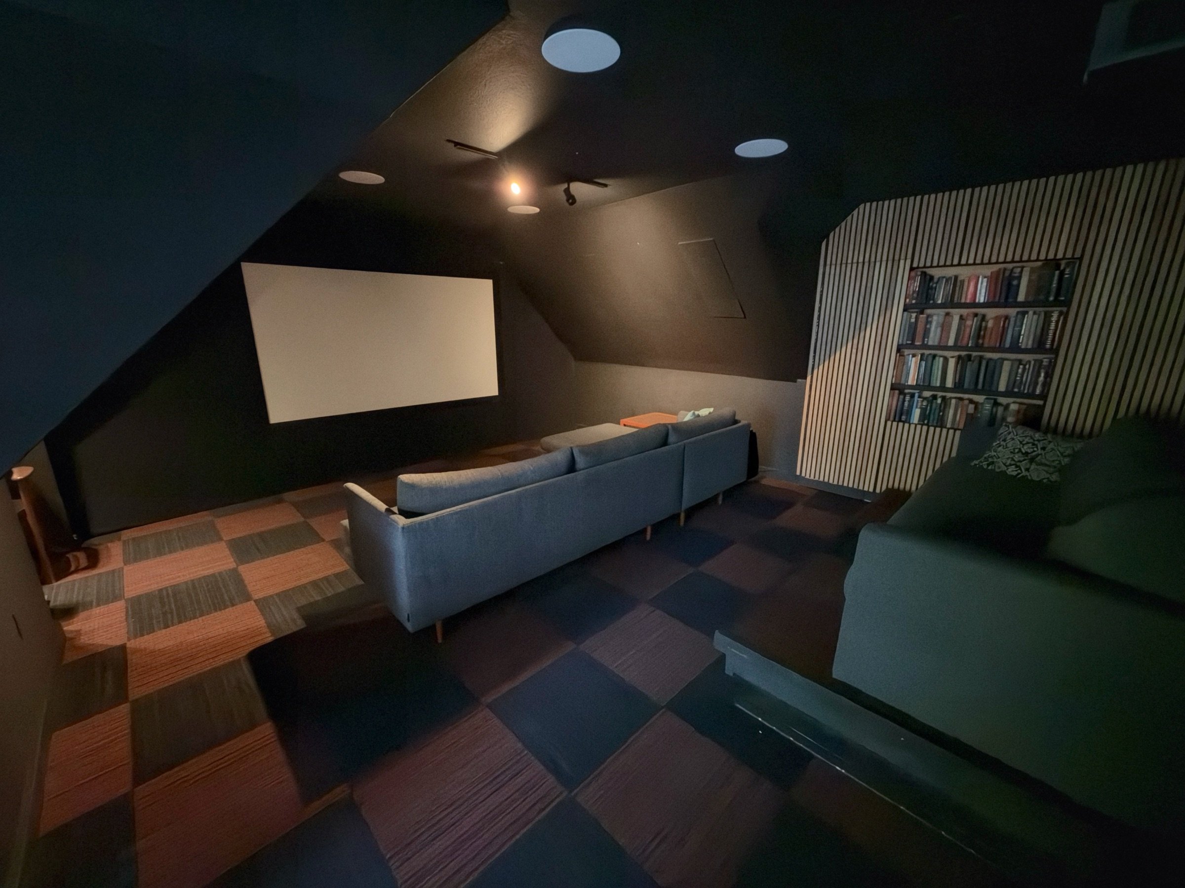 Our Gig Harbor showroom cinema, with the projection screen on the left, blue sofa in the center and green sofa beside the bookshelf