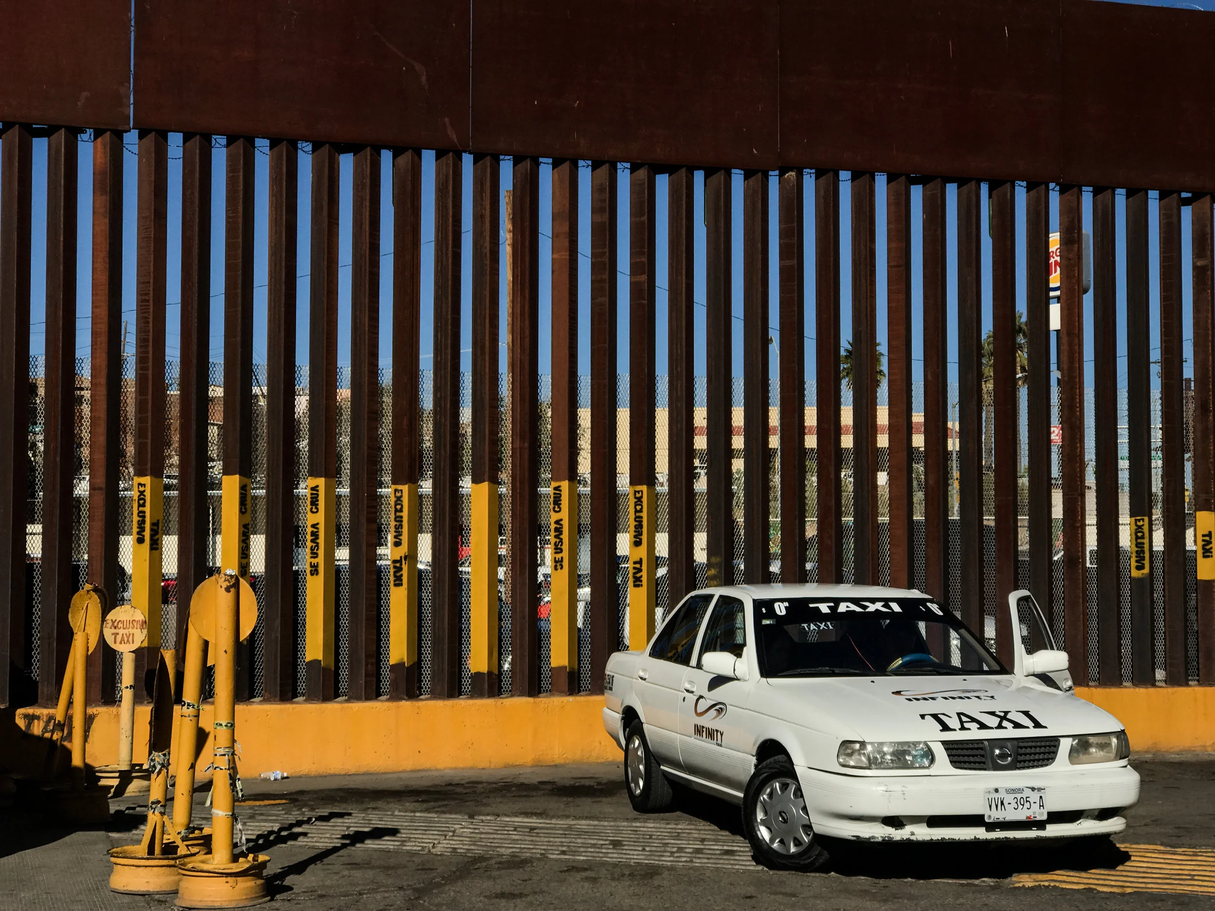 Signage painted directly on the border fence for a "taxis only" parking area in Nogales, Mexico