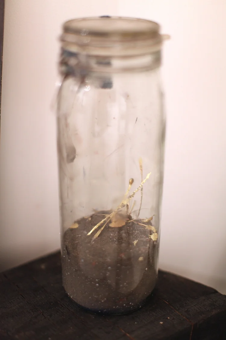 Detail of installation: remnants and dust of metal sculptures in a jar
