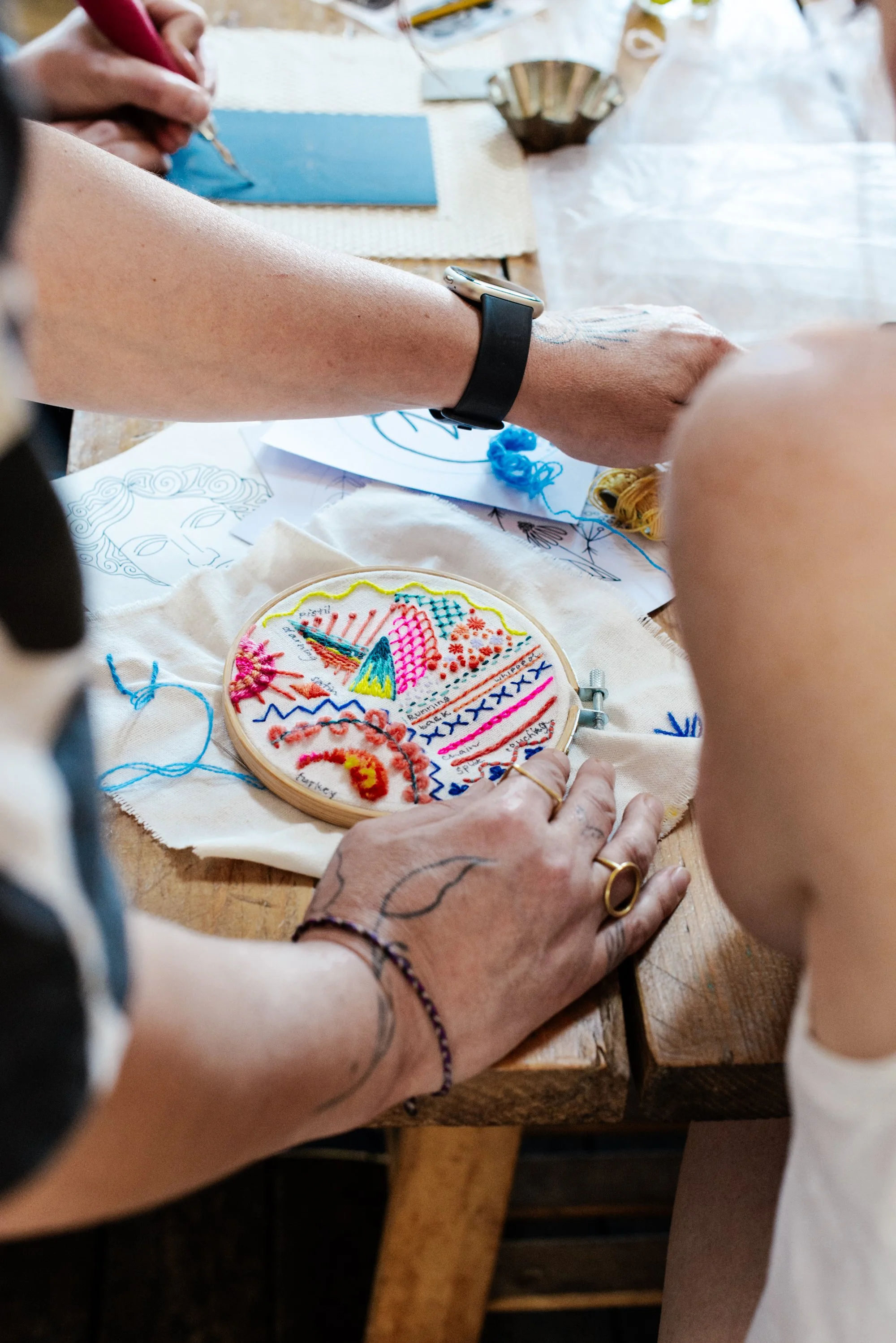 Colourful embroidery workshop at The Forge in Bristol with guests creating textile artwork around a shared table.