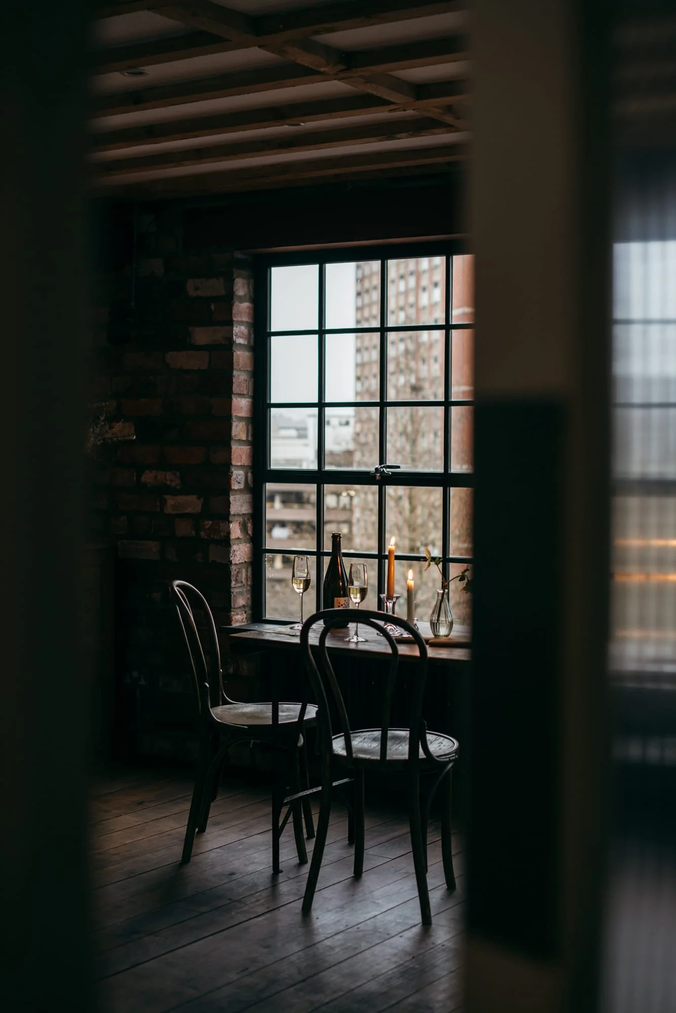 Moody industrial wedding venue interior at The Forge Bristol with candlelight, exposed brickwork and large steel-framed windows