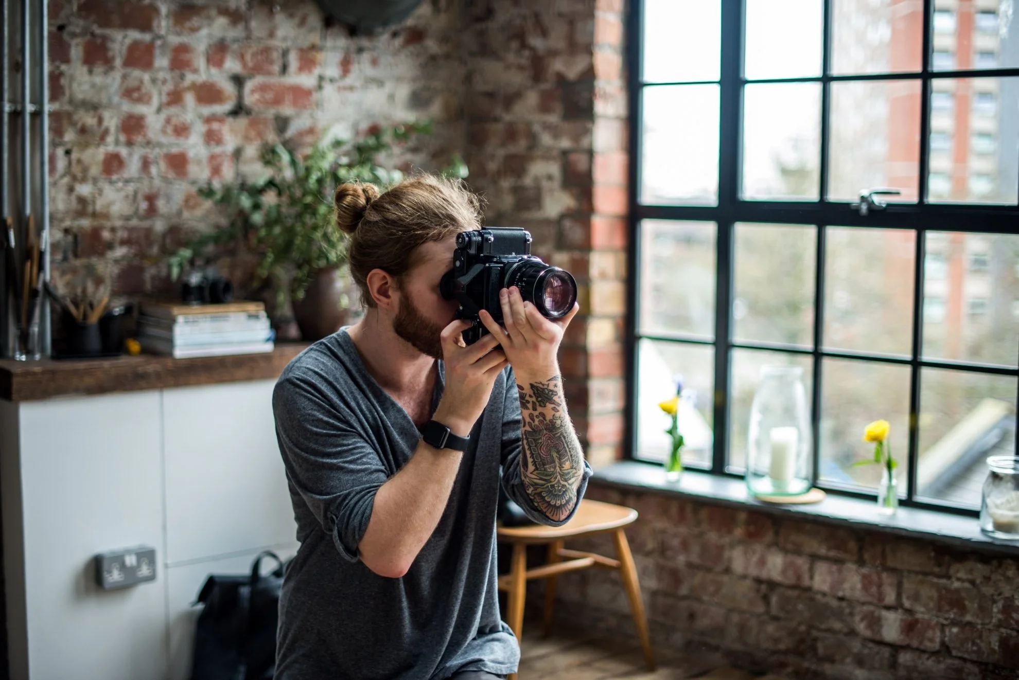 A photographer captures the moment in a characterful loft-style location with exposed brick, natural light, and stylish details—available to hire for film and photography in Bristol