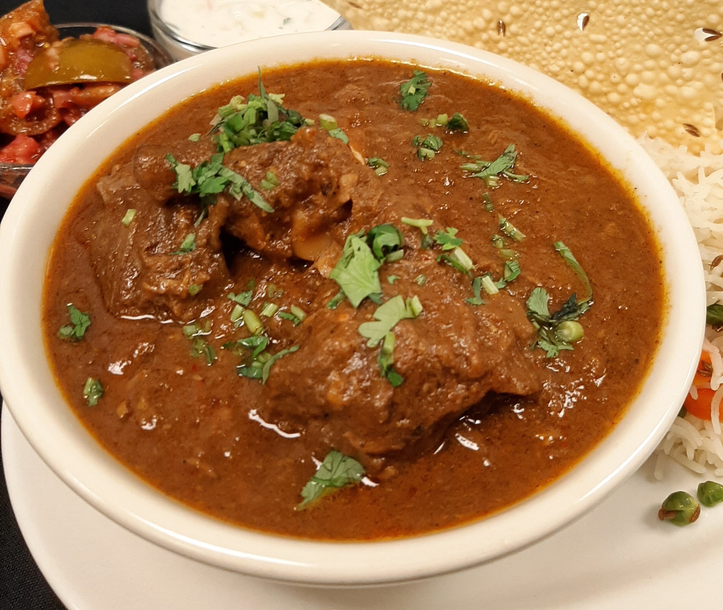 Mutton Curry Tender goat simmered with ginger, garlic, tomato, onions, and whole spices