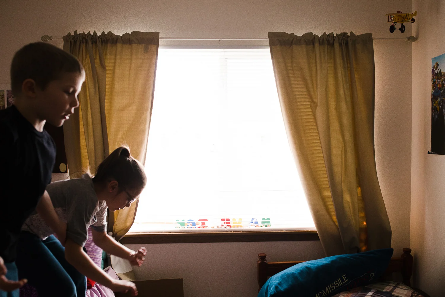 brother and sister jumping on their bed