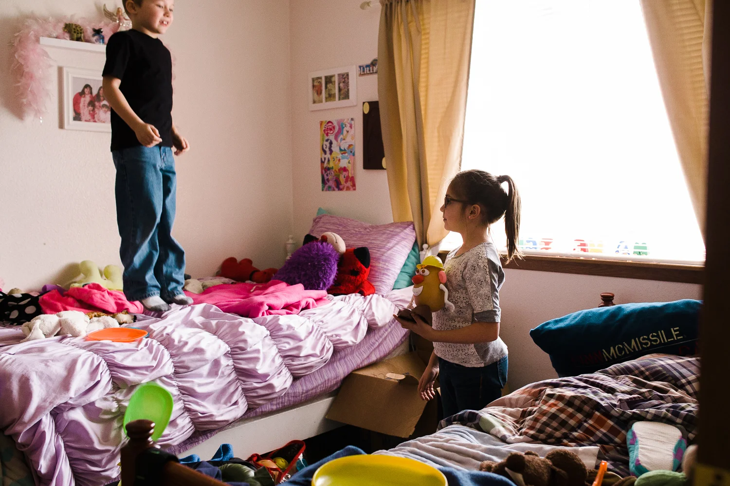 brother and sister jumping on their bed