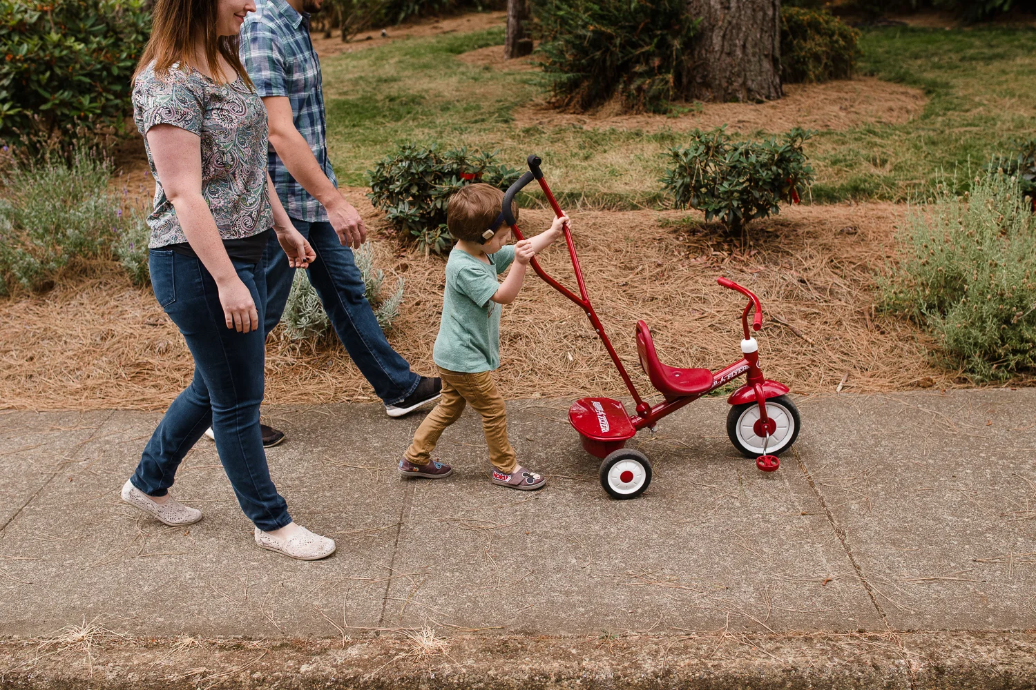 boy pushing his red bike