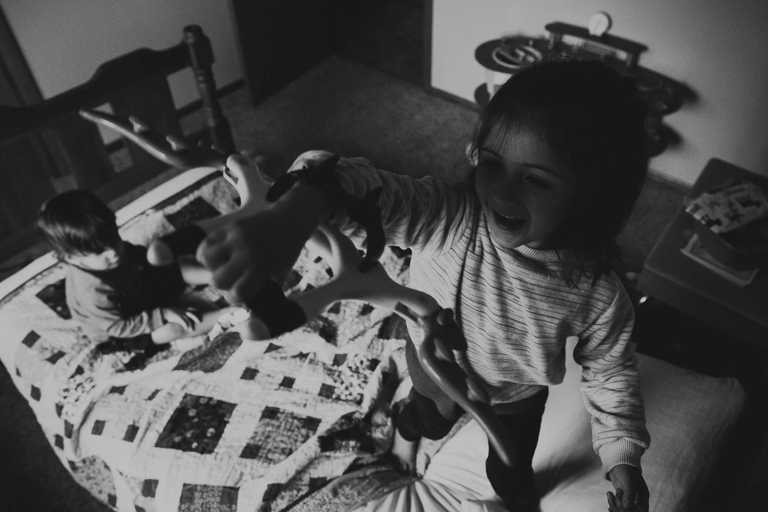 brother and sister playing on bed
