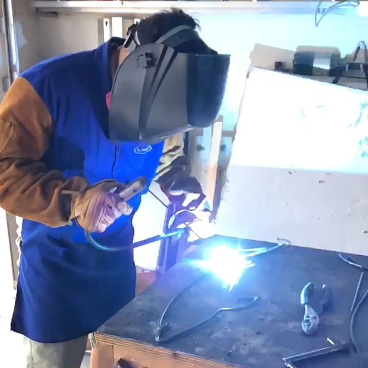 Artist Norman Silva welding steel rods for one of his sculptures with welding gear on.