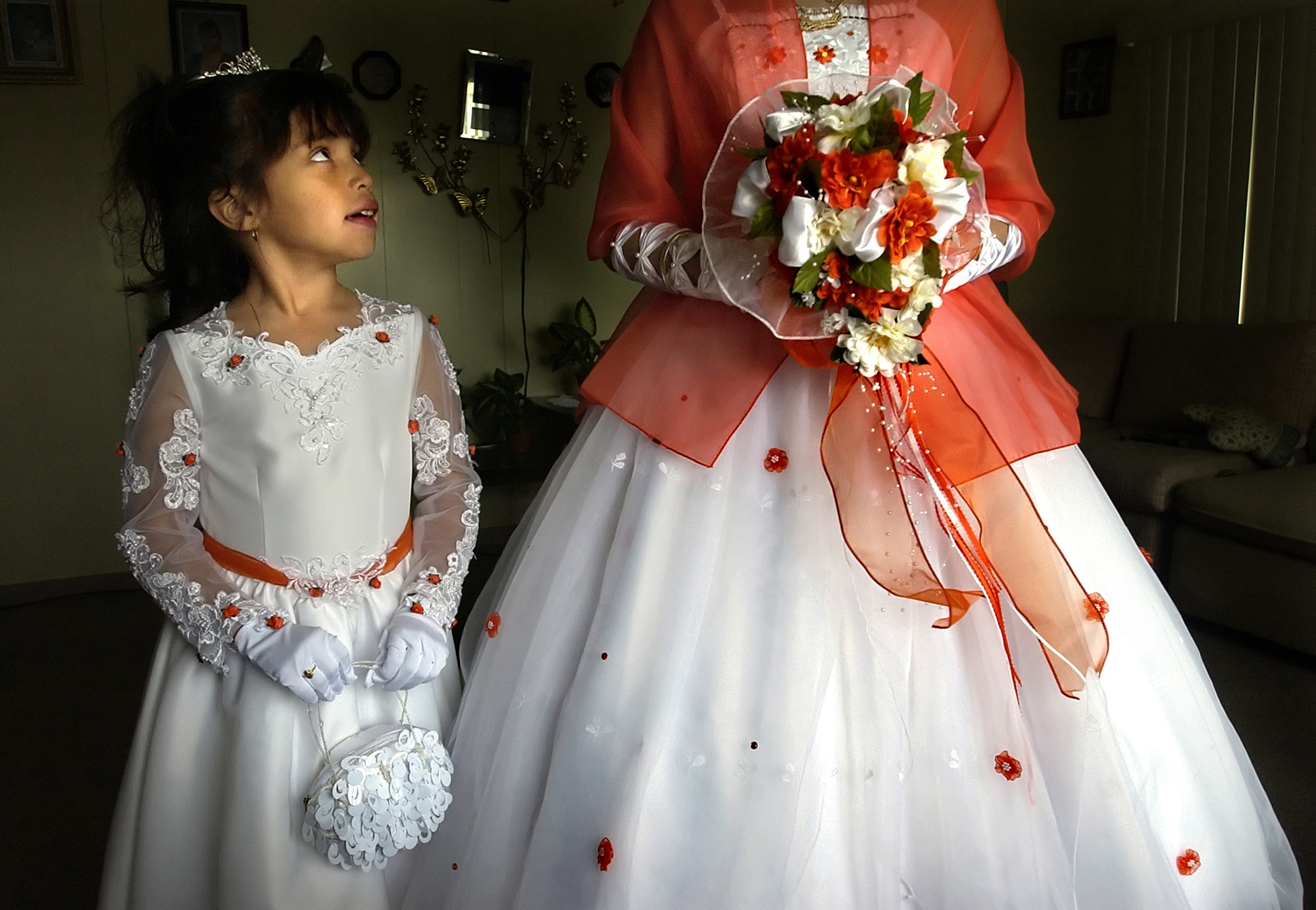 Seven-year-old Belia eyes Anayeli prior to Anayeli's Quinceanera in Traverse City. A Quinceanera is an important and lavish Mexican cultural tradition marking the 15th birthday of a young girl. It symbolizes the transition from girlhood to becoming a woman. Anayeli's Quinceanera brought together over 300 people from the migrant and agriculture community.