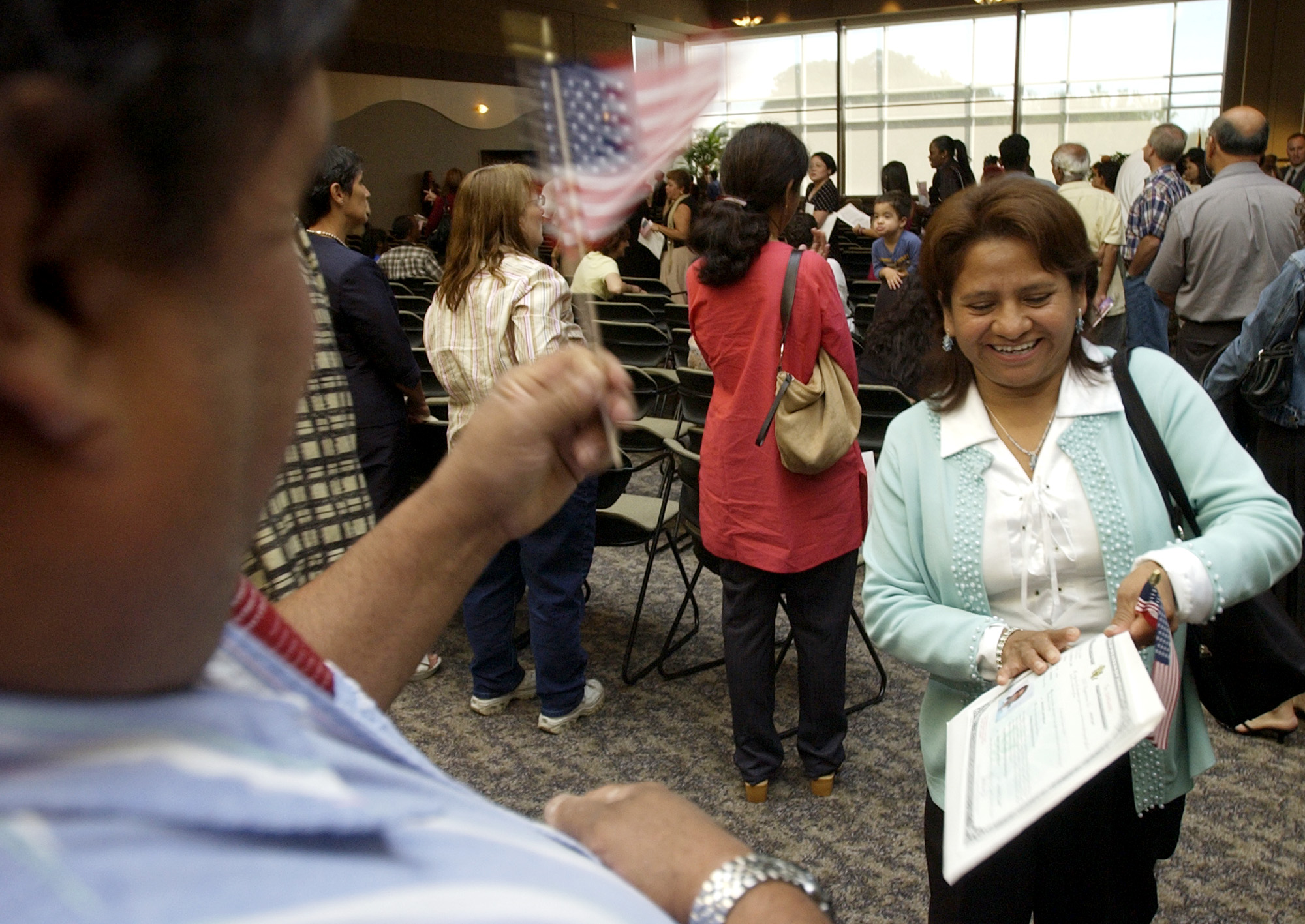 Francisco Nuno waves the American flag in celebration of wife Tomasa Nuno's during her participation in a naturalization ceremony of new immigrants at the Frederik Meijer Gardens & Sculpture Park in Grand Rapids. Nuno, a native of Guerrero, Mexico has lived in Michigan for the past decade. Tomasa's husband Francisco Nuno, son Javier Nuno, and daughter Lorena Ramirez have all become naturalized, and their youngest daughter Patricia, 7, was born an American citizen. Nationally, immigration became a political hot button issue, which emboldened Tomasa to become an American citizen so she could vote in the 2006 mid-term elections. 