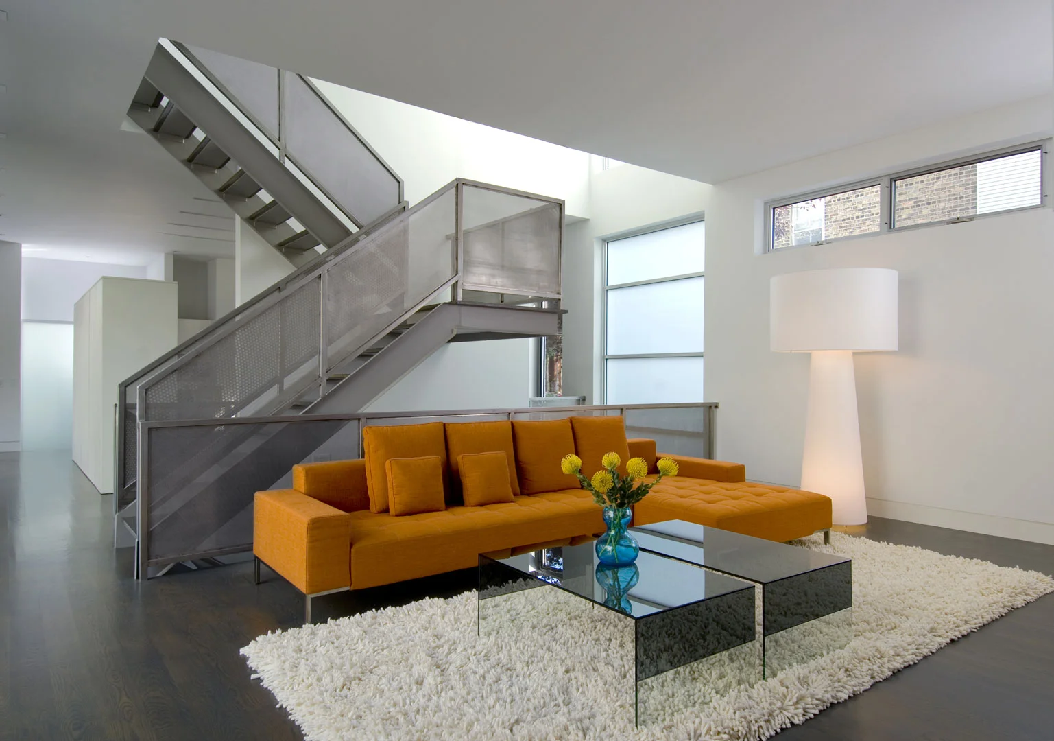 Single-Family Location: Chicago, IL Photos: Marty Peters 2008 Residential Architect Design Award Program This custom residence was created out of the basic elements in architecture-light, shadow, massing, color, transition and how we experience these things. The house was to be a collection of light-play in a tight urban setting. A residential Box Set. The residence is located on a tight urban lot in Chicago's older Bucktown neighborhood. It is for a young urban couple with three young children and a Mother-in-Law. The residence faces north. The size of the house was to be approximately 6500 square feet in area and comprise of 4 levels. The garden level required an office for the owners, a guest suite, den for the kids, an exercise room and spa bath. The first floor required a living room, dining room, kitchen and family room. The second floor was for the master bedroom suite, two kid’s rooms and an open reading loft. The third floor required an entertaining room which includes a kitchen and a full roof deck with views of the city skyline. The owners also requested a series of exterior spaces located on different levels; courtyard, garage roof deck and house roof deck. Solution The design solution started with two cubes, one opaque and one transparent. Both cubes are paired together to create an “L” shape and define an inner courtyard. All rooms face the inner courtyard. Like a Box Set, the transparent cube collects the majority of the light for the residence and allows for views through the residence from the street and other areas of the home. The opaque cube accommodates the more private functions of the residence. This residence is designed using very simple strategies. The exterior is clad in only two materials; white ground face masonry and cedar. The white masonry creates open and light filled interiors while the cedar is used as natural, softening accent. Both materials extend to the interiors to create subtle contrasting surfaces and blur the boundary between the exterior and the interior. The second floor ceiling of the transparent cube is clad in cedar that extends through the house, projecting out each side, providing sun protection.