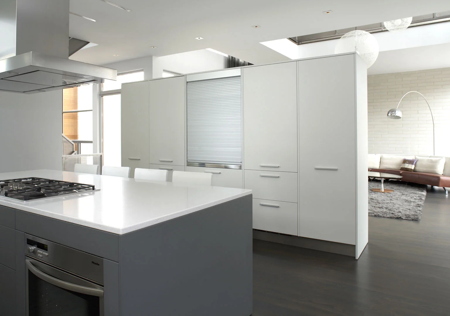 Single-Family Location: Chicago, IL Photos: Marty Peters 2008 Residential Architect Design Award Program This custom residence was created out of the basic elements in architecture-light, shadow, massing, color, transition and how we experience these things. The house was to be a collection of light-play in a tight urban setting. A residential Box Set. The residence is located on a tight urban lot in Chicago's older Bucktown neighborhood. It is for a young urban couple with three young children and a Mother-in-Law. The residence faces north. The size of the house was to be approximately 6500 square feet in area and comprise of 4 levels. The garden level required an office for the owners, a guest suite, den for the kids, an exercise room and spa bath. The first floor required a living room, dining room, kitchen and family room. The second floor was for the master bedroom suite, two kid’s rooms and an open reading loft. The third floor required an entertaining room which includes a kitchen and a full roof deck with views of the city skyline. The owners also requested a series of exterior spaces located on different levels; courtyard, garage roof deck and house roof deck. Solution The design solution started with two cubes, one opaque and one transparent. Both cubes are paired together to create an “L” shape and define an inner courtyard. All rooms face the inner courtyard. Like a Box Set, the transparent cube collects the majority of the light for the residence and allows for views through the residence from the street and other areas of the home. The opaque cube accommodates the more private functions of the residence. This residence is designed using very simple strategies. The exterior is clad in only two materials; white ground face masonry and cedar. The white masonry creates open and light filled interiors while the cedar is used as natural, softening accent. Both materials extend to the interiors to create subtle contrasting surfaces and blur the boundary between the exterior and the interior. The second floor ceiling of the transparent cube is clad in cedar that extends through the house, projecting out each side, providing sun protection.