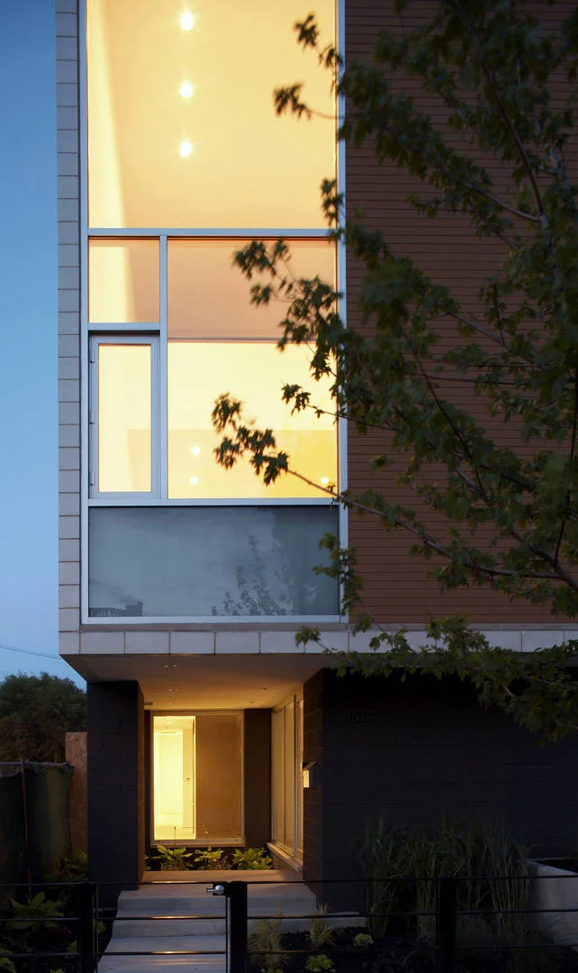 Single-Family Location: Chicago, IL Photos: Marty Peters Program This custom residence was created out of the basic elements in architecture-light, shadow, massing, color, transition and how we experience these things. The owner requested one thing; “…create a home that no matter my mood or frame of mind, it makes me forget even my worst day in calming surroundings filled with light”. The intention was to create a light filled retreat in a tight urban setting. A residential Light Box. The residence is located on a narrow urban lot in Chicago's older Bucktown neighborhood. It is for a young urban couple. The residence faces east and is bound on its north and south by neighboring buildings as close as three feet, rising four stories. The size of the house was to be approximately 6000 square feet in area and comprise of 4 levels. Because the residence was to be four stories, the main living level was located on the second floor, taking advantage of the garage roof as exterior urban space. The first level required an office for the owners, a den, an exercise room and spa bath. The second floor required a living room, dining room, kitchen and family room. The third floor was for the bedrooms and an open reading loft. The fourth floor was for the master bedroom suite, and the roof level was for entertaining, including a full roof deck with views of the city skyline. The owners also requested a series of exterior spaces located on different levels; courtyard, garage roof deck and house roof deck. Solution The design solution started with an urban box and the notion of “light” and how to move light throughout the house. The box was given carved openings on the ends in addition to a large hidden inner light court that introduces natural sunlight into the center of the residence. Because the entire residence is conceived of as one solid rectangle, openings in it and carved areas shift its scale, drawing attention to its subtle detail. Windows for different rooms were grouped to strengthen the shift in scale. The first floor was also set back, carved and clad in dark masonry to give hierarchy to its upper white masonry clad main levels. The masonry is carefully articulated in a stacked bond pattern reinforcing the orthogonal nature of the residence. This residence is designed using very simple strategies. The exterior is mainly clad in only two materials; white masonry and cedar, with a small amount charcoal masonry used at the first floor base. The white masonry creates open and light filled interiors while the cedar is used as natural, softening accent. Both materials extend to the interiors to create subtle contrasting surfaces and blur the boundary between the exterior and the interior.