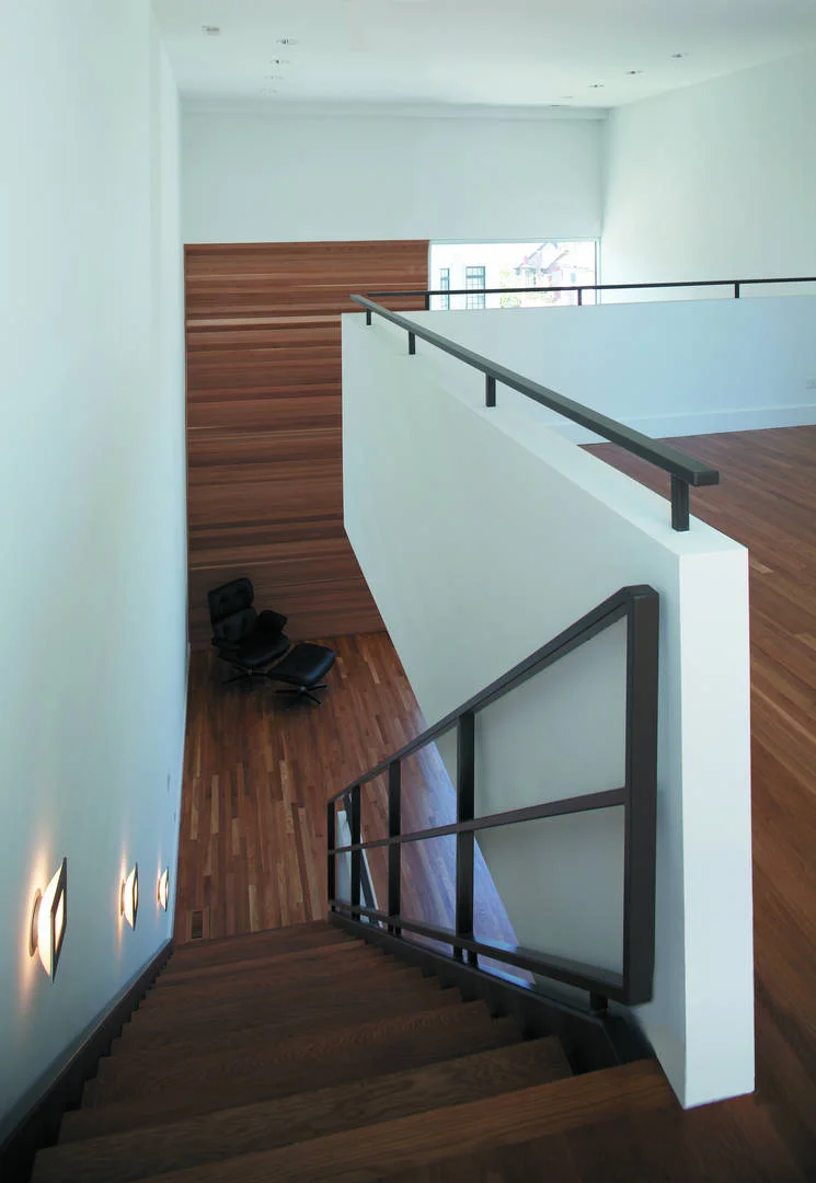 Single-Family Location: Chicago, IL Photos: Marty Peters Program This custom residence was created out of the basic elements in architecture-light, shadow, massing, color, transition and how we experience these things. The owner requested one thing; “…create a home that no matter my mood or frame of mind, it makes me forget even my worst day in calming surroundings filled with light”. The intention was to create a light filled retreat in a tight urban setting. A residential Light Box. The residence is located on a narrow urban lot in Chicago's older Bucktown neighborhood. It is for a young urban couple. The residence faces east and is bound on its north and south by neighboring buildings as close as three feet, rising four stories. The size of the house was to be approximately 6000 square feet in area and comprise of 4 levels. Because the residence was to be four stories, the main living level was located on the second floor, taking advantage of the garage roof as exterior urban space. The first level required an office for the owners, a den, an exercise room and spa bath. The second floor required a living room, dining room, kitchen and family room. The third floor was for the bedrooms and an open reading loft. The fourth floor was for the master bedroom suite, and the roof level was for entertaining, including a full roof deck with views of the city skyline. The owners also requested a series of exterior spaces located on different levels; courtyard, garage roof deck and house roof deck. Solution The design solution started with an urban box and the notion of “light” and how to move light throughout the house. The box was given carved openings on the ends in addition to a large hidden inner light court that introduces natural sunlight into the center of the residence. Because the entire residence is conceived of as one solid rectangle, openings in it and carved areas shift its scale, drawing attention to its subtle detail. Windows for different rooms were grouped to strengthen the shift in scale. The first floor was also set back, carved and clad in dark masonry to give hierarchy to its upper white masonry clad main levels. The masonry is carefully articulated in a stacked bond pattern reinforcing the orthogonal nature of the residence. This residence is designed using very simple strategies. The exterior is mainly clad in only two materials; white masonry and cedar, with a small amount charcoal masonry used at the first floor base. The white masonry creates open and light filled interiors while the cedar is used as natural, softening accent. Both materials extend to the interiors to create subtle contrasting surfaces and blur the boundary between the exterior and the interior.