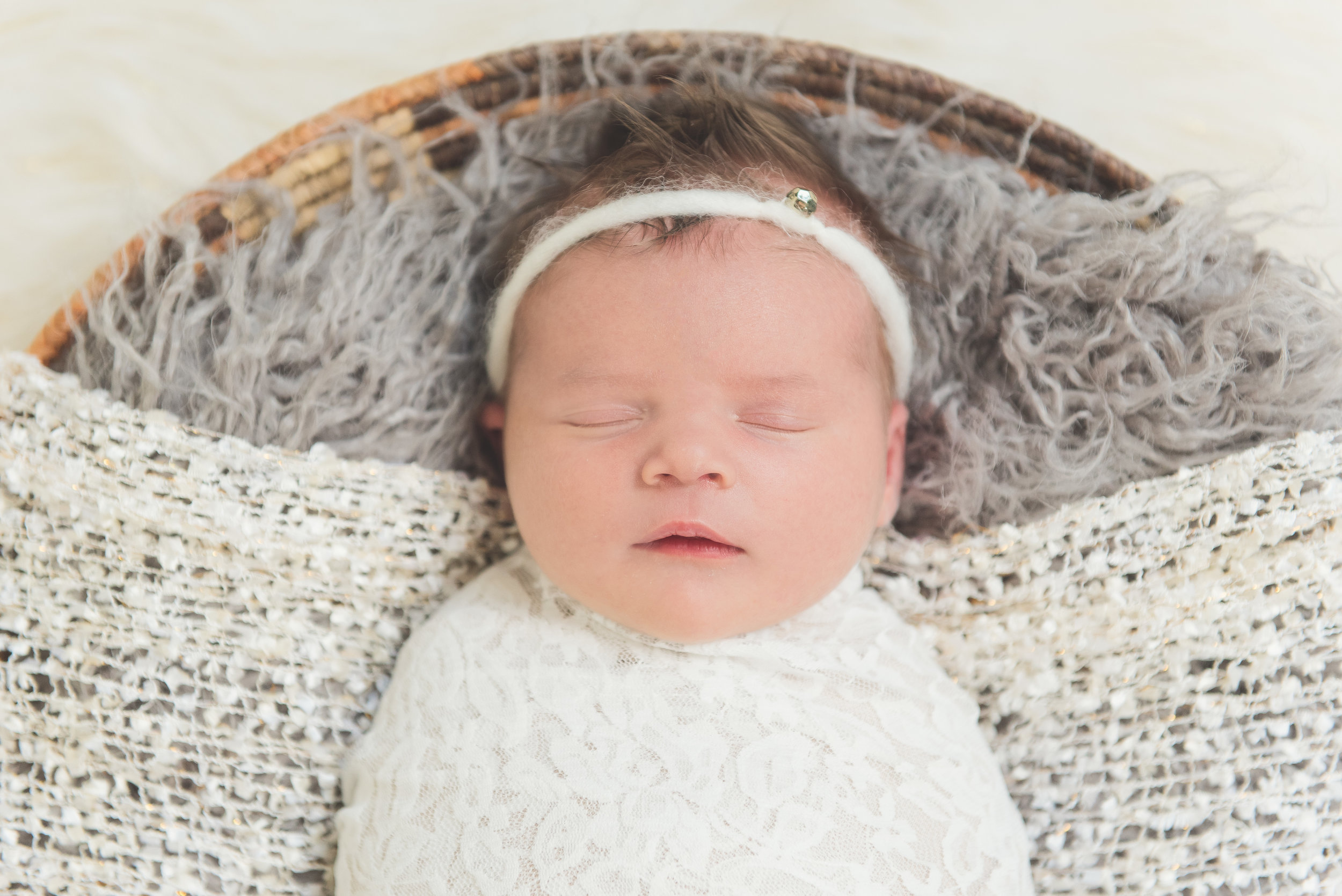 newborn girl in basket with diamond headband
