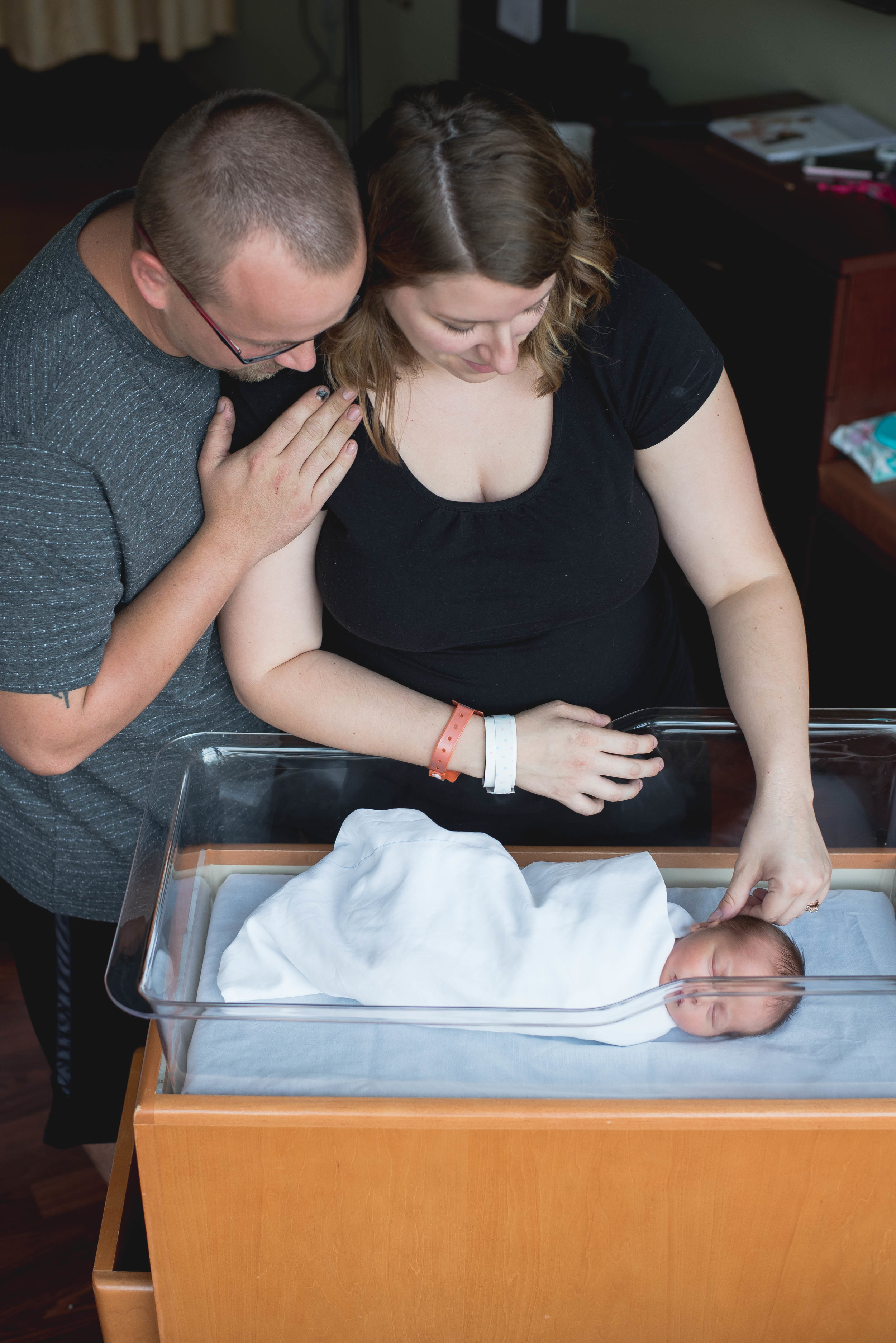 mom and dad with baby in bassinet