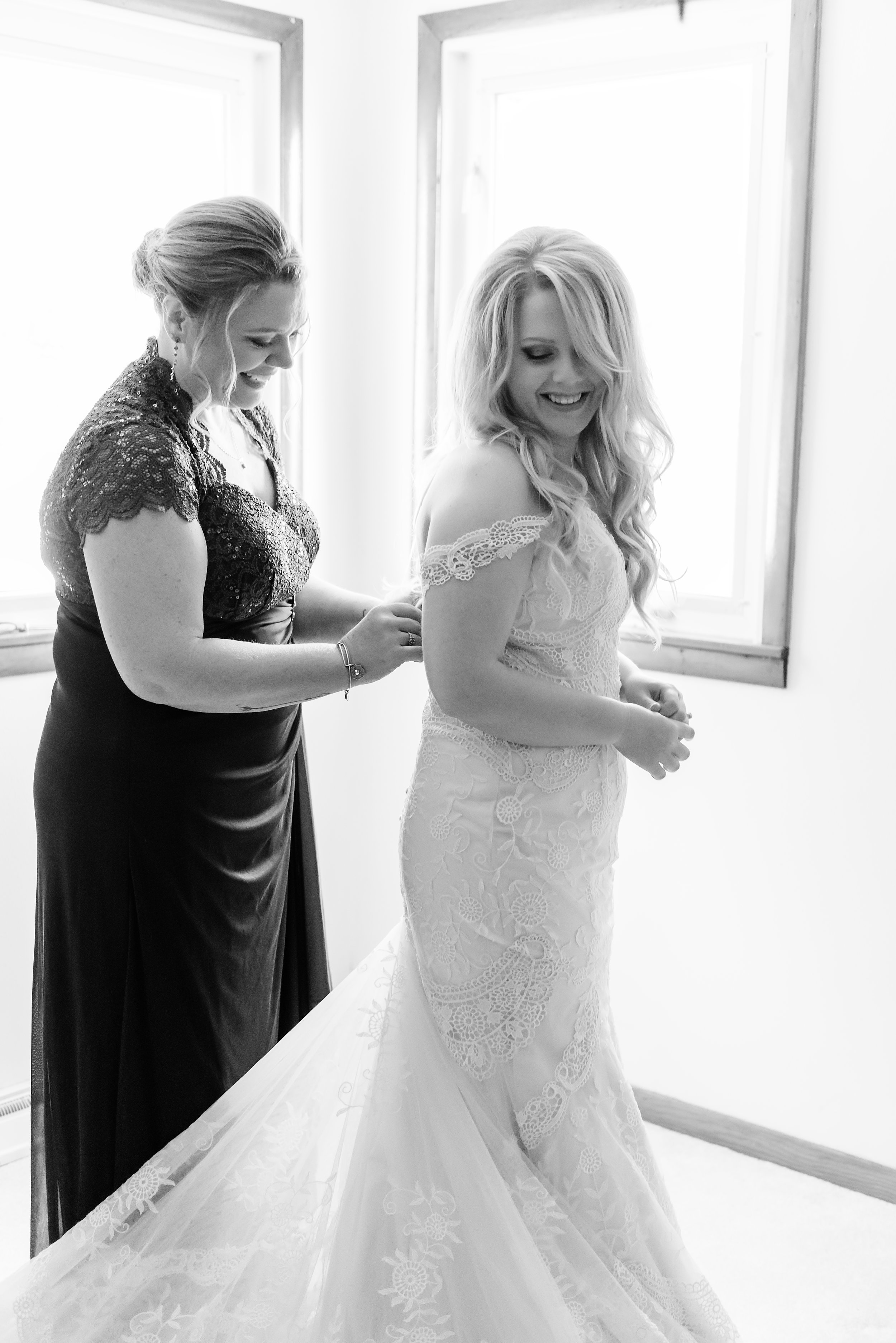 mom helping bride into dress