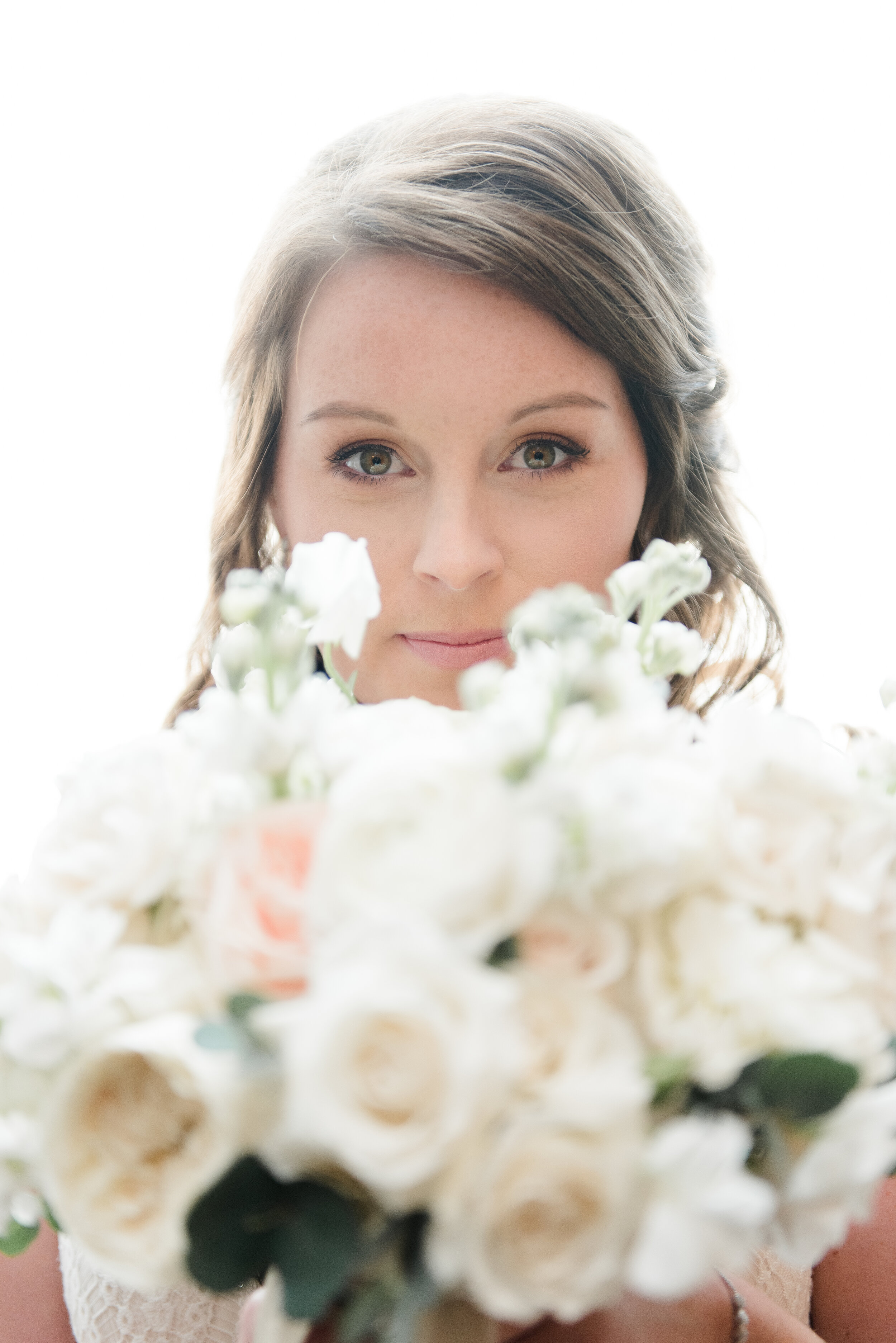Bridal portrait hiding behind bouquet