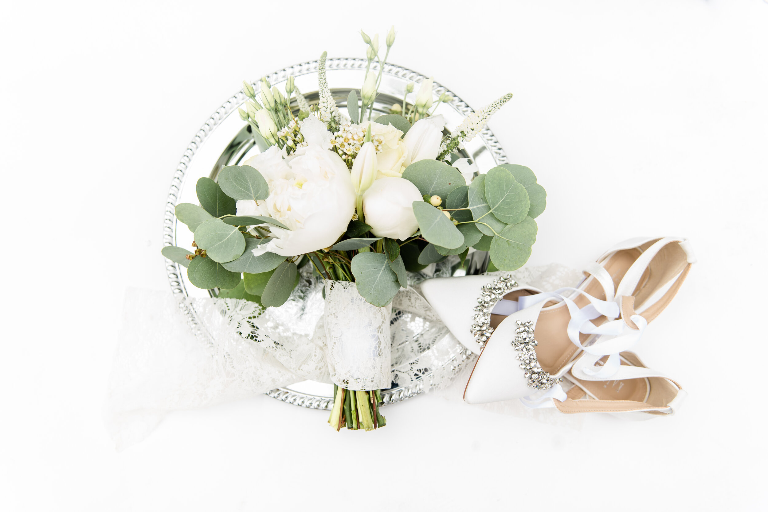 silver platter with wedding bouquet and white bridal shoes