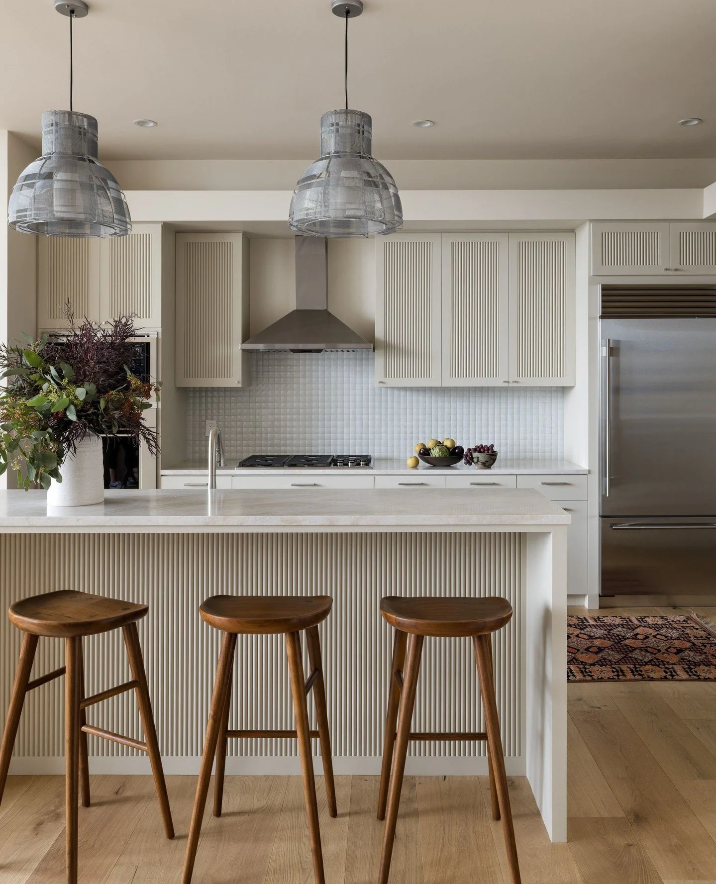 By painting the existing cabinets in the kitchen of our Seattle Skyline Project, we were able to add a new island. We then custom-matched the vertical detail from the cabinets on the counter facade, creating cohesion in a fresh way. Counters and back