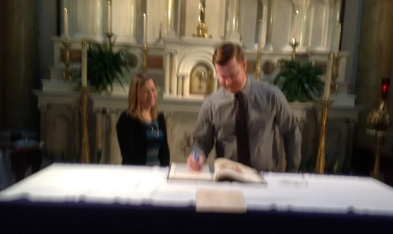 MATT CURRIER, CATECHUMEN, SIGNING THE "BOOK OF THE ELECT"