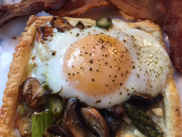 Egg Galette: A savory breakfast puff pastry topped with farm fresh sauteed mushrooms and asparagus topped with a soft yolked egg.