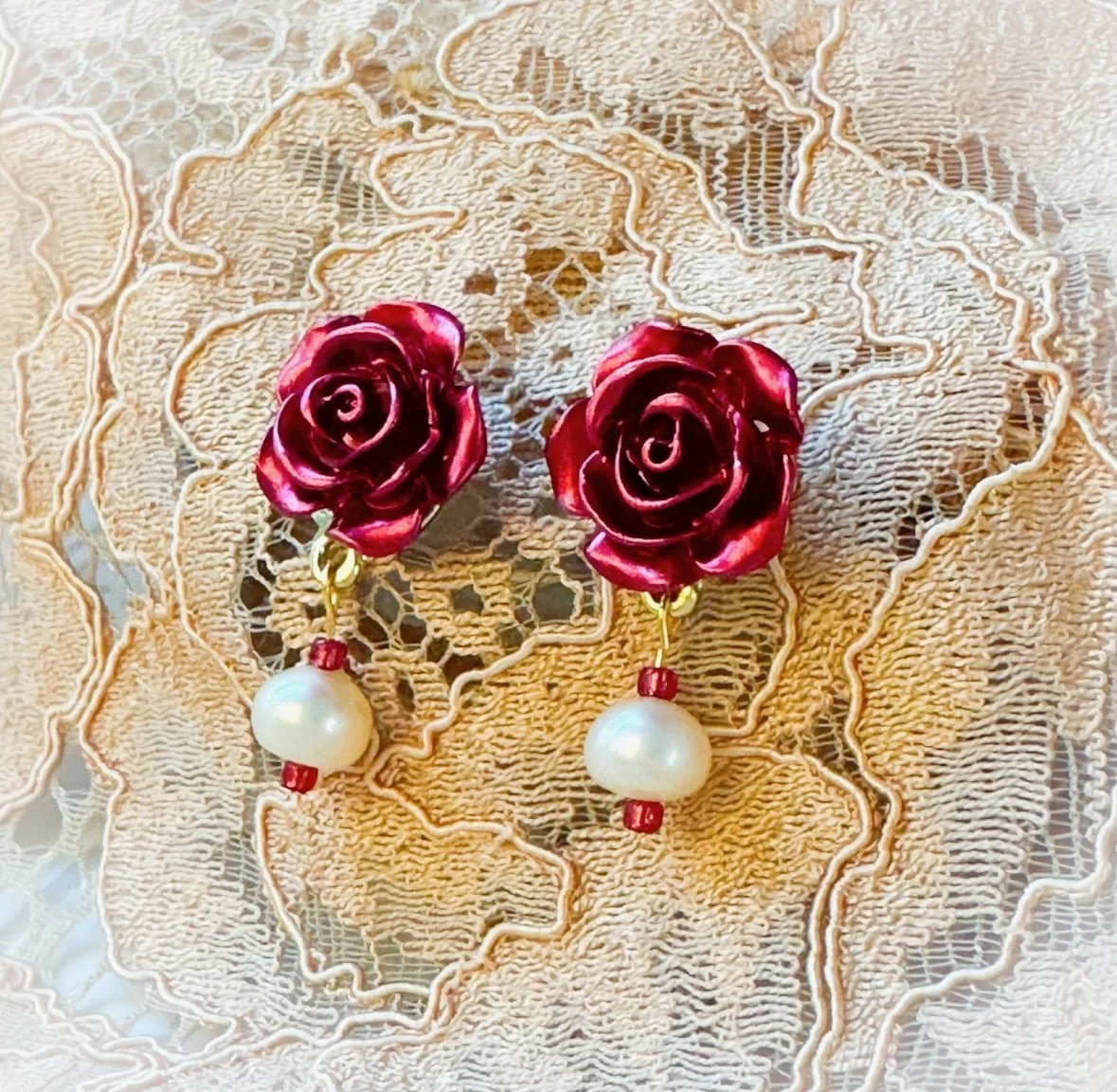 rose stud earrings with real pearls on a lace background.