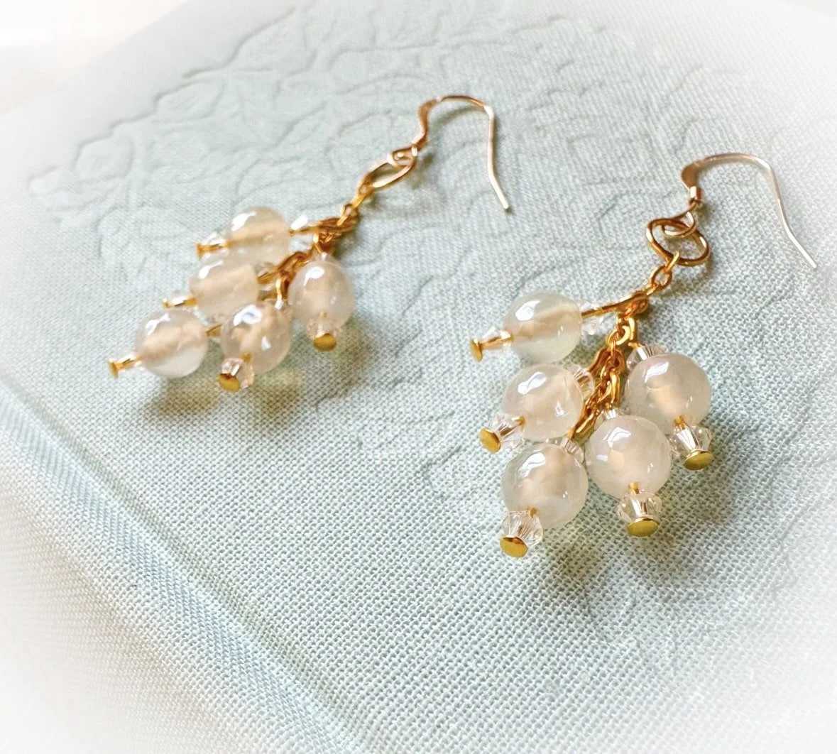 mystic agate dangle earrings on pale blue book