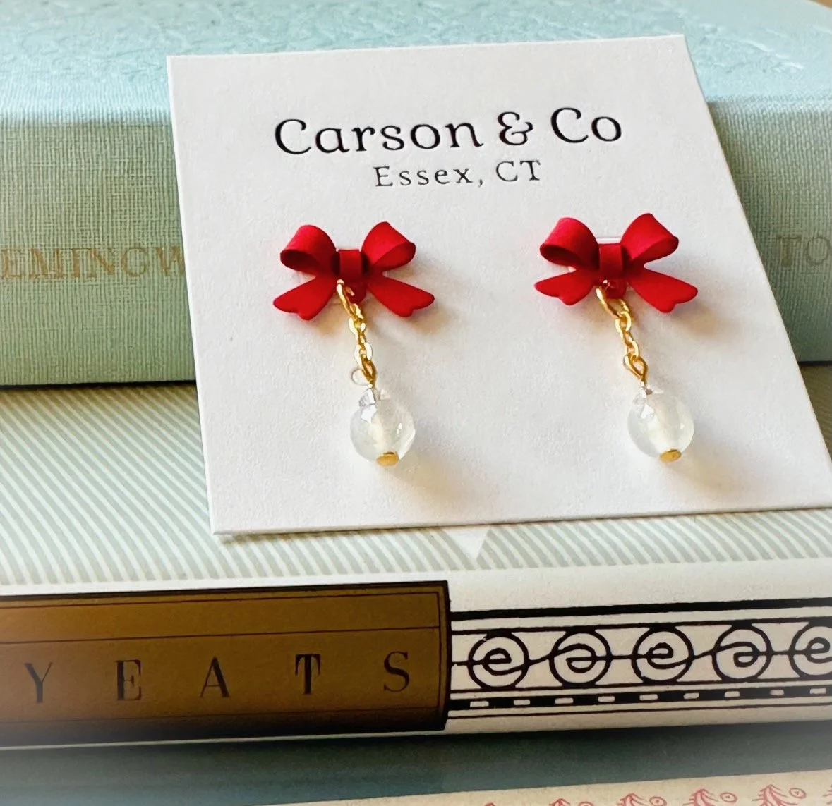 One pair of red bow earrings sitting on two books.