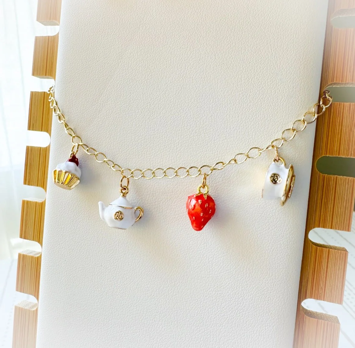 Charm bracelet with teacup, teapot, cupcake and strawberry.