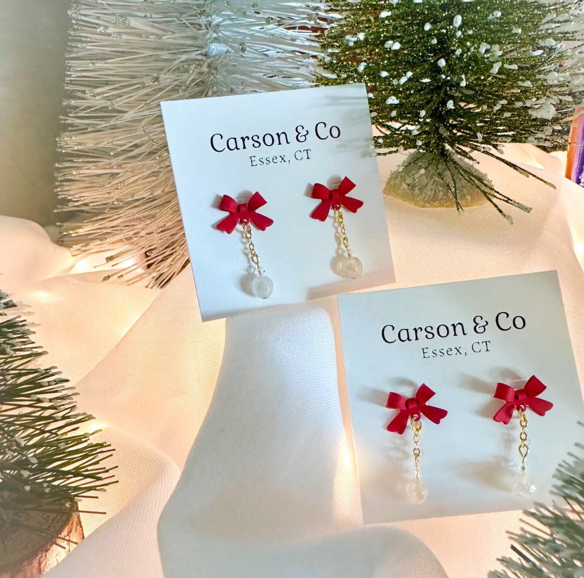 Red Christmas bow earrings with sparkly lights and Christmas trees.