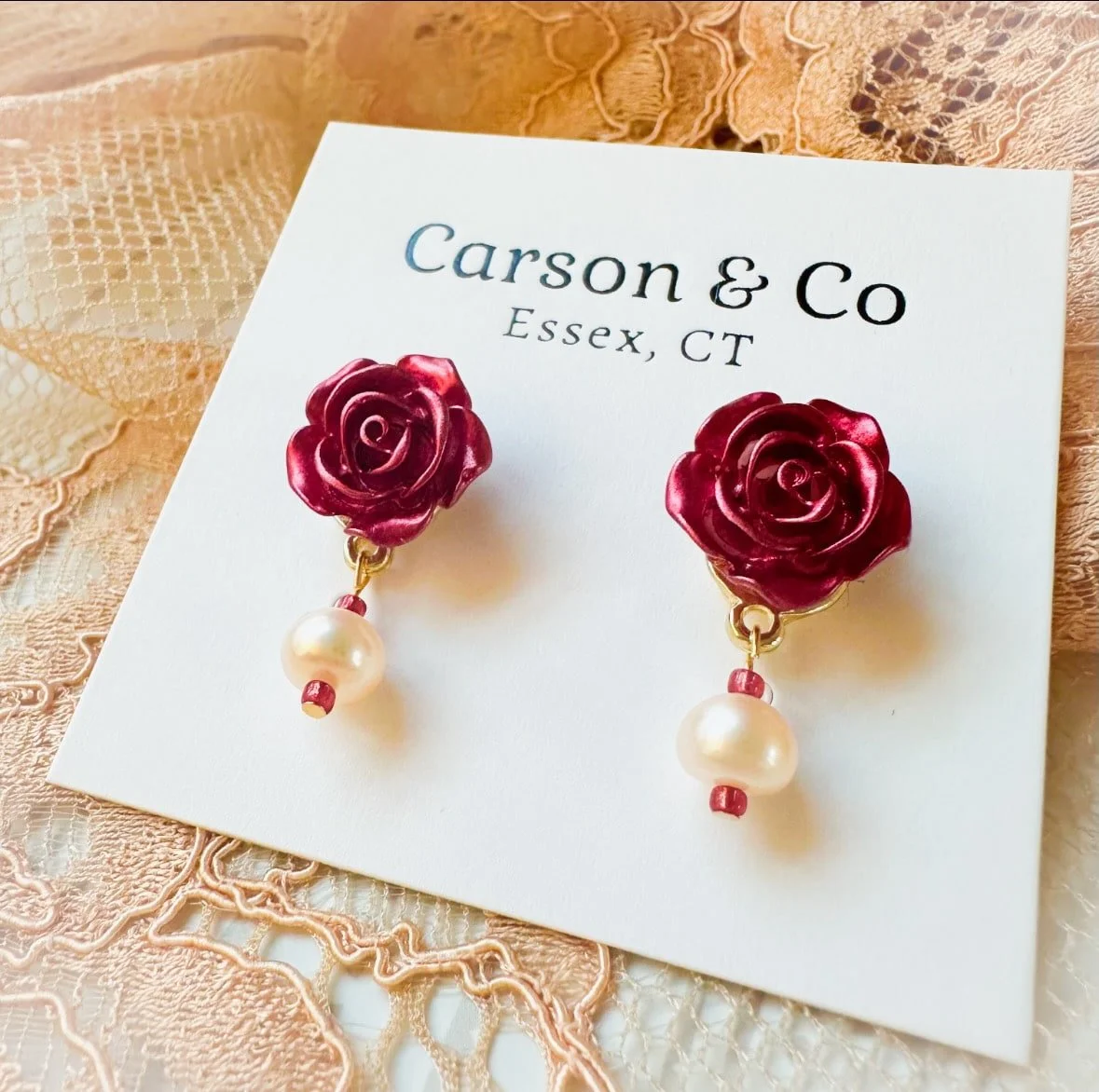rose stud earrings with real pearls on a lace background.