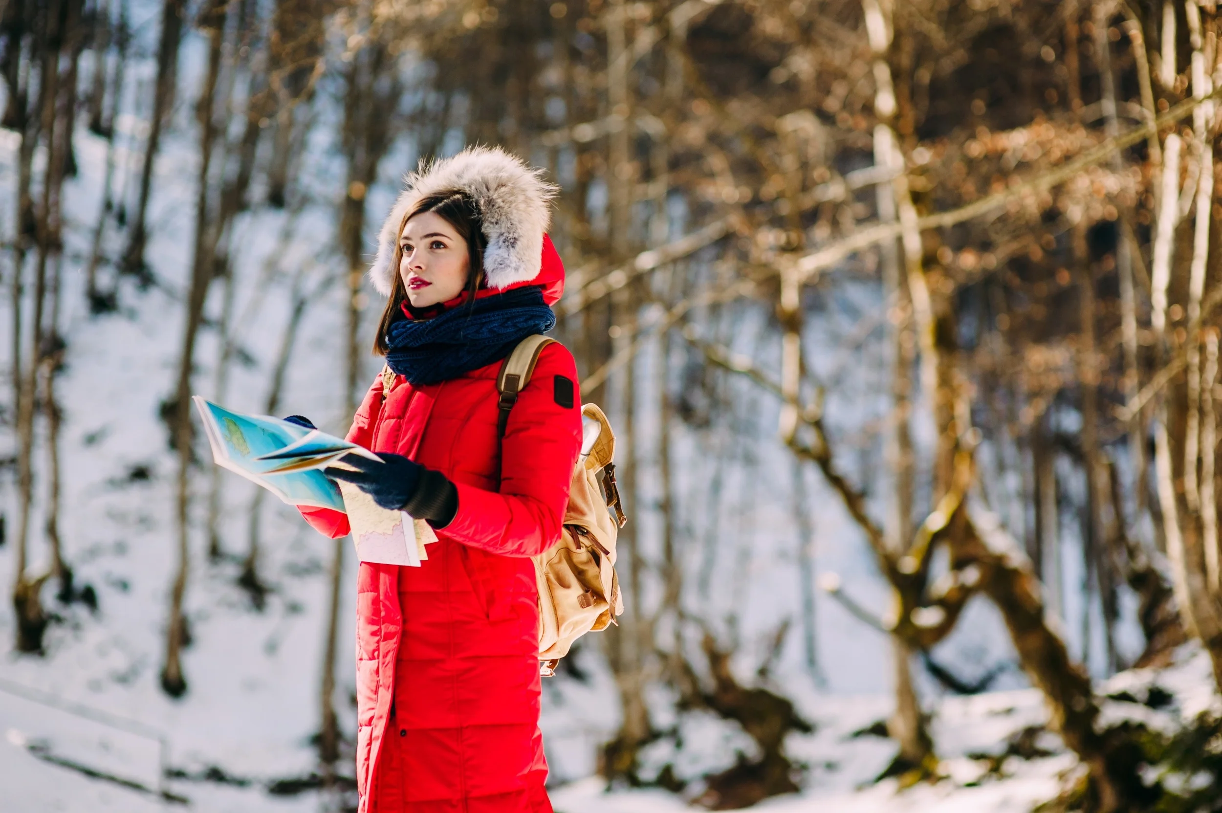 Hiker looking for the way on the map in snow forest