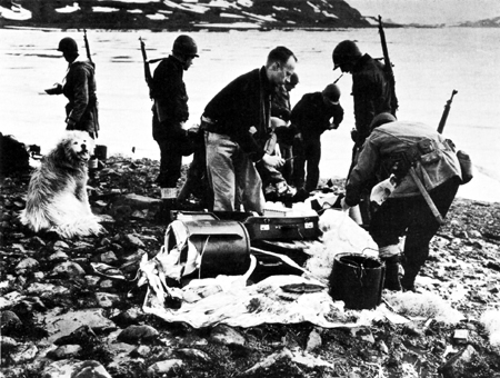 Members of the Sled Patrol examine captured parachute equipment at the site of an abandoned German station. Source: US Coast Guard