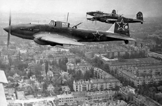 A group of Il-2M3s fly low above a devastated city.