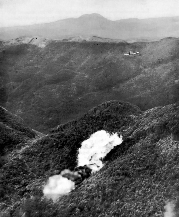 An F4U Corsair drops napalm on a Japanese position while operating in close air support of Marine forces on the ground