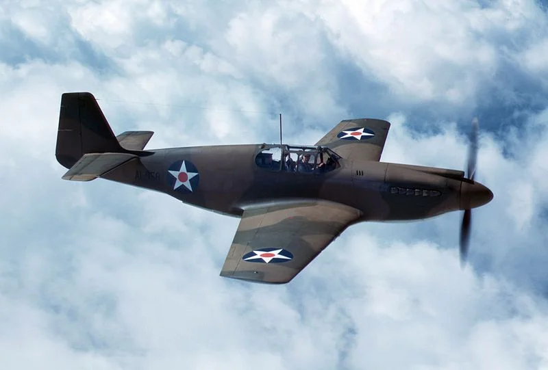 A P-51A, one of the first delivered to the British. Red roundels on the stars indicate this photograph was likely taken in late 1941 or early 1942, before the marking was deleted from US insignia. The camouflage pattern is British, painted at the factory by North American. Source: Wikipedia.