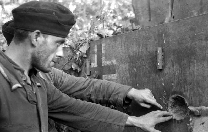 Tiger crewmen examine the impact mark left behind from a shell that failed to penetrate the Tiger's armor. It appears that this impact was on one of the sides of the tank. Photo source: Wikipedia.