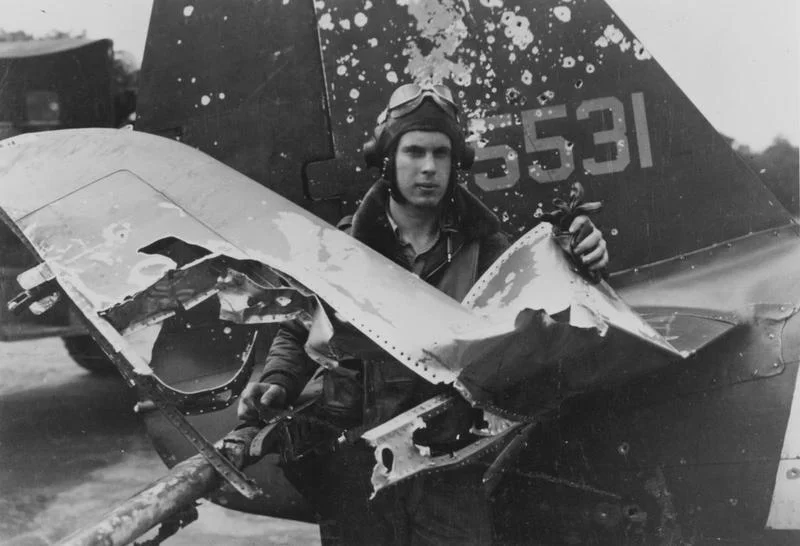 Another pilot stands among the remains of his right horizontal stabilizer, which was clearly hit by flak, spraying shrapnel into the tail and fuselage. This kind of damage was not at all uncommon during the dangerous close air support and ground att…