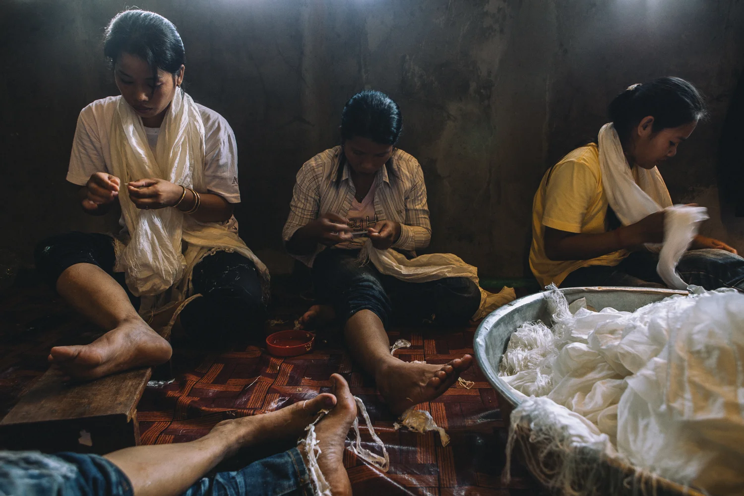 Workers sort through strands of silk to create scarf tassels