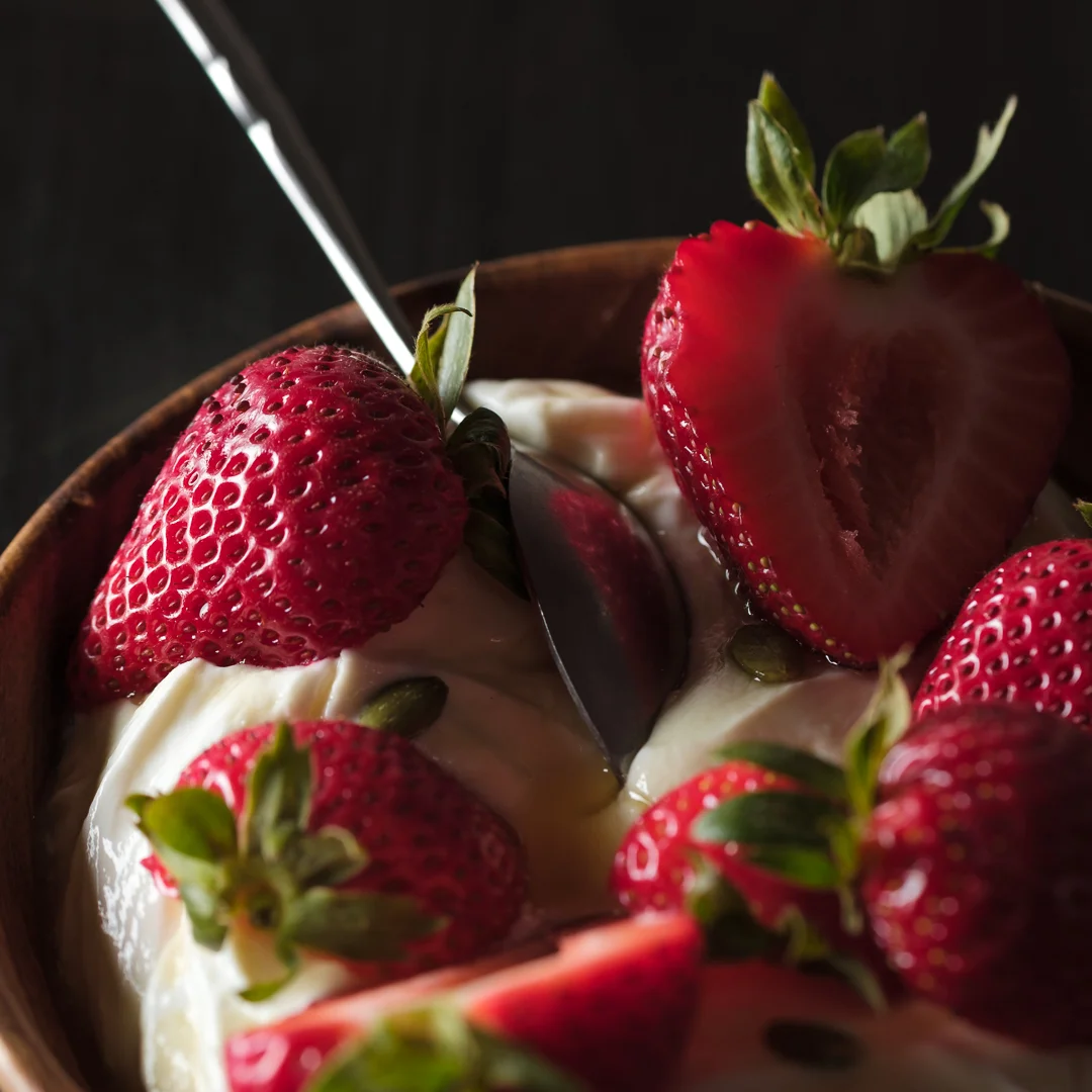 Strawberries and Greek Yogurt Seasonally fresh strawberries over Greek yogurt and local honey in a wooden carved bowl.