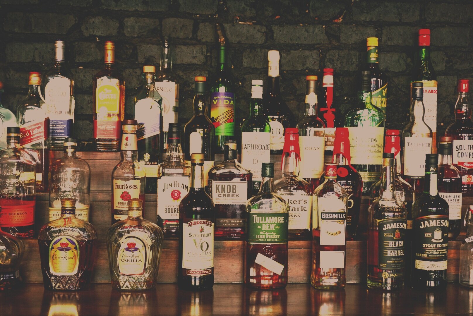  Multiple liquor bottles on display on a four-tier shelf showcasing the liquors available. 