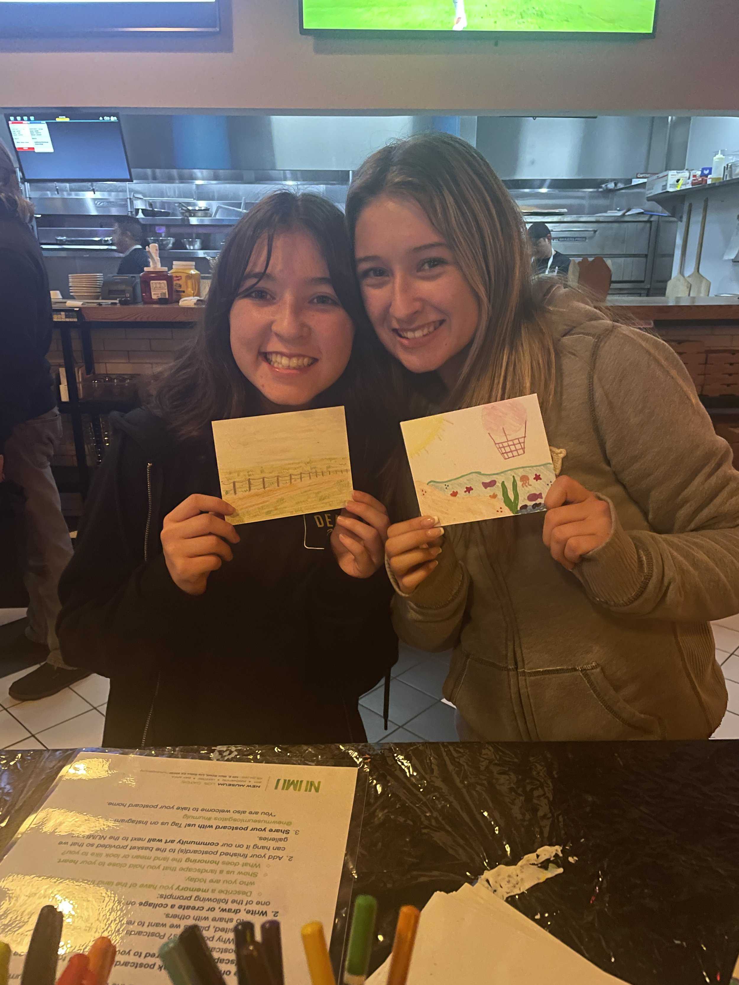 Two teenage girls posing with their postcards
