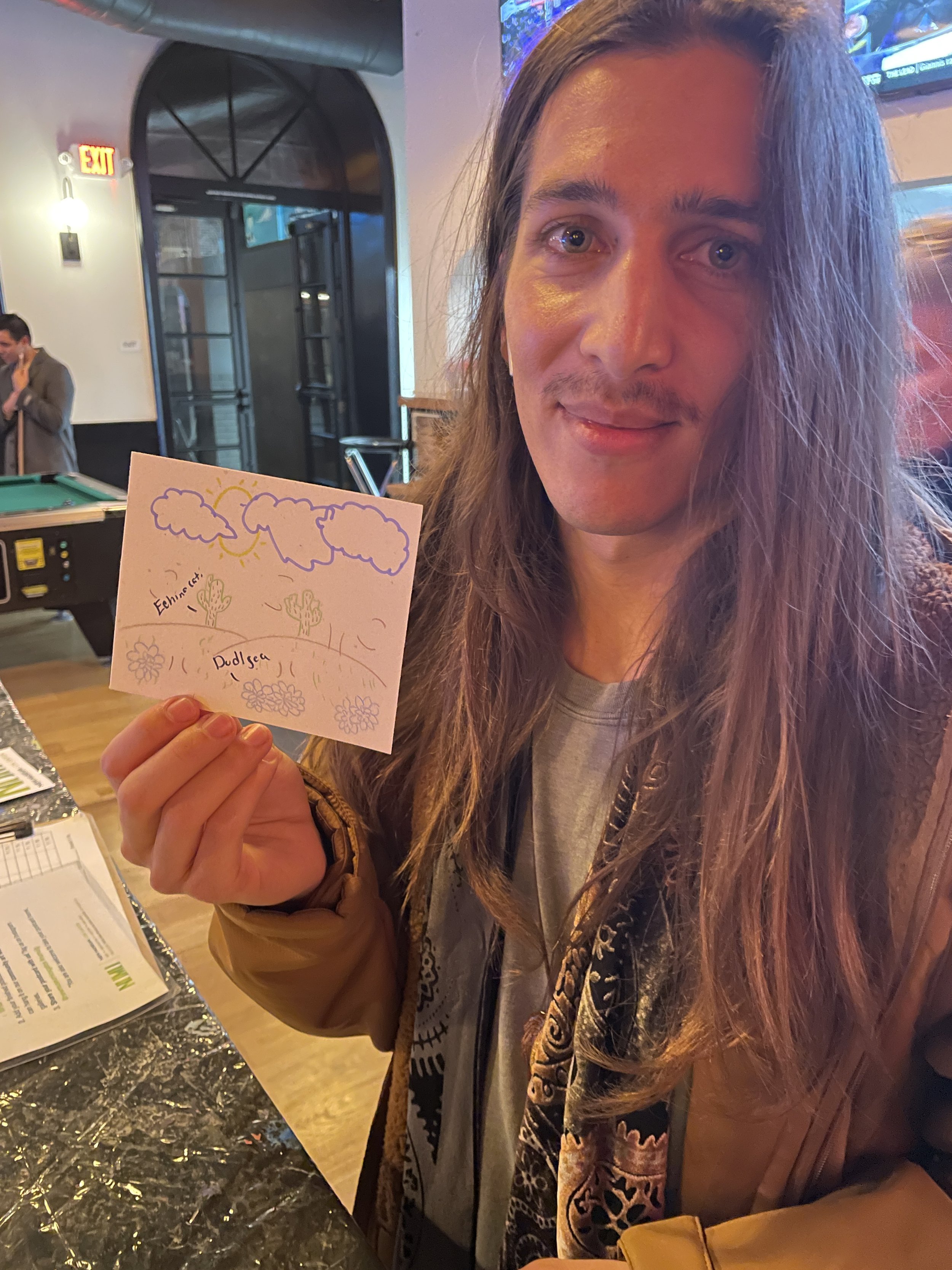A man holding up his postcard of drawn clouds