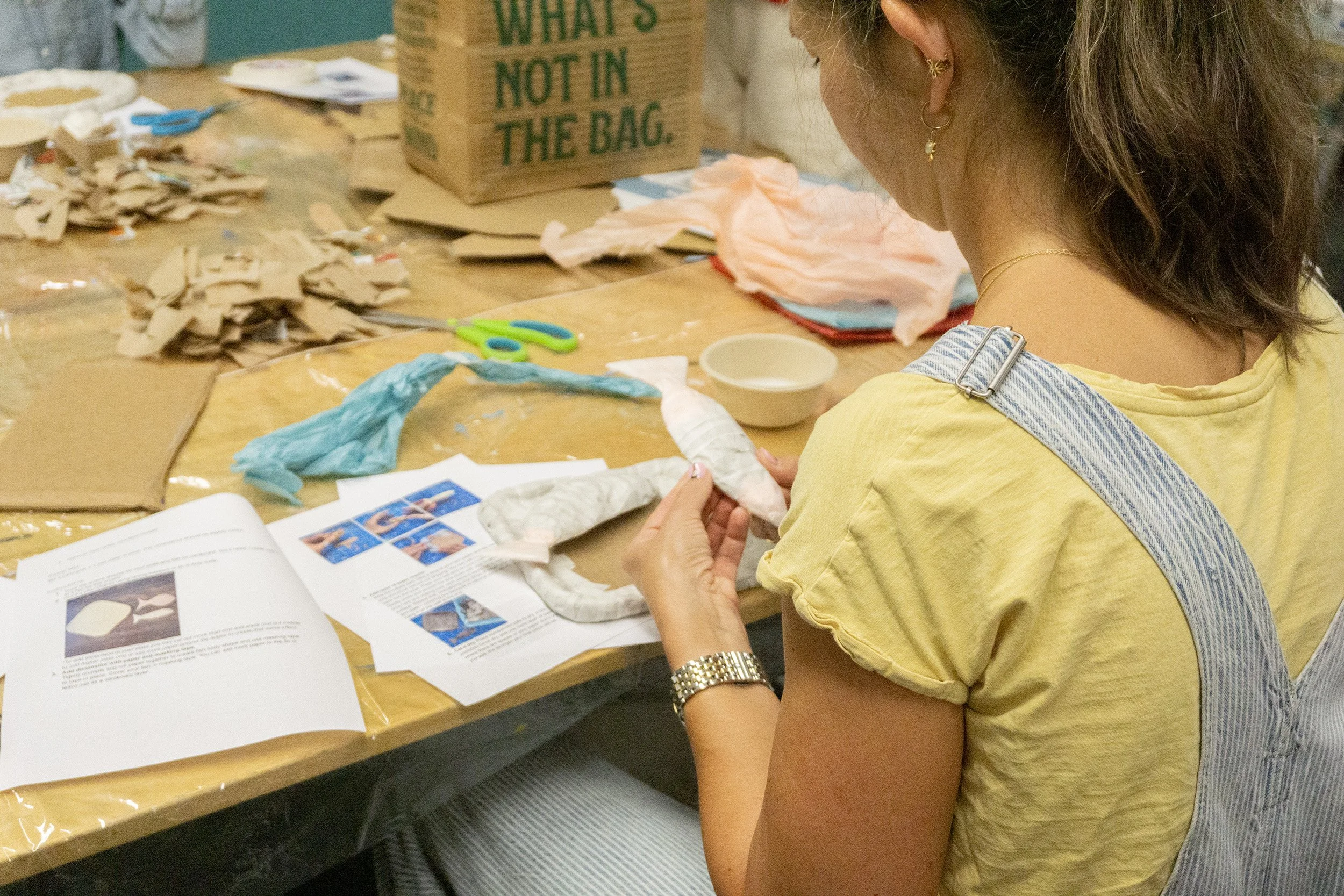 A behind-the-shoulder shot of a woman making papier-mâché