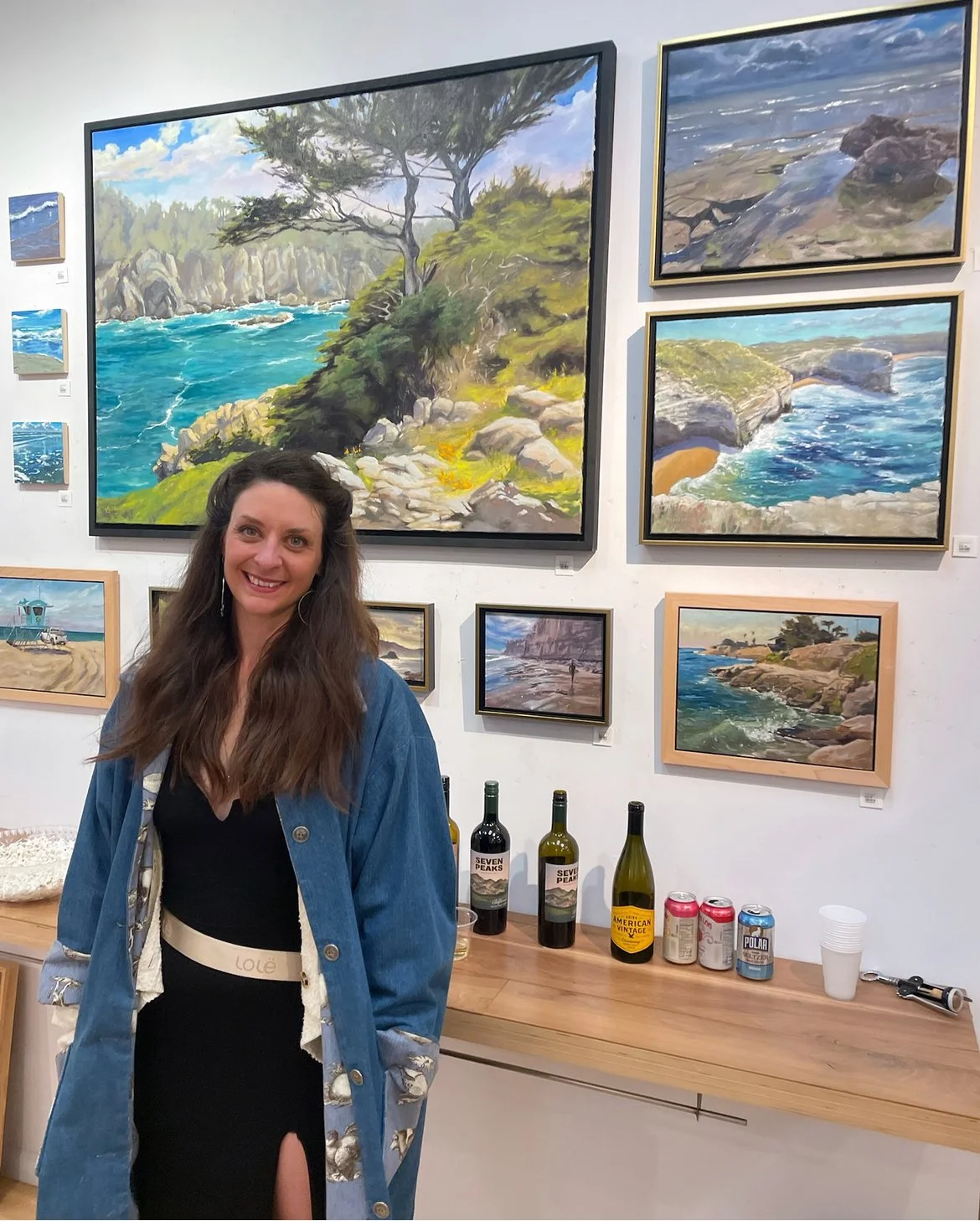 A woman poses in front of framed seascapes